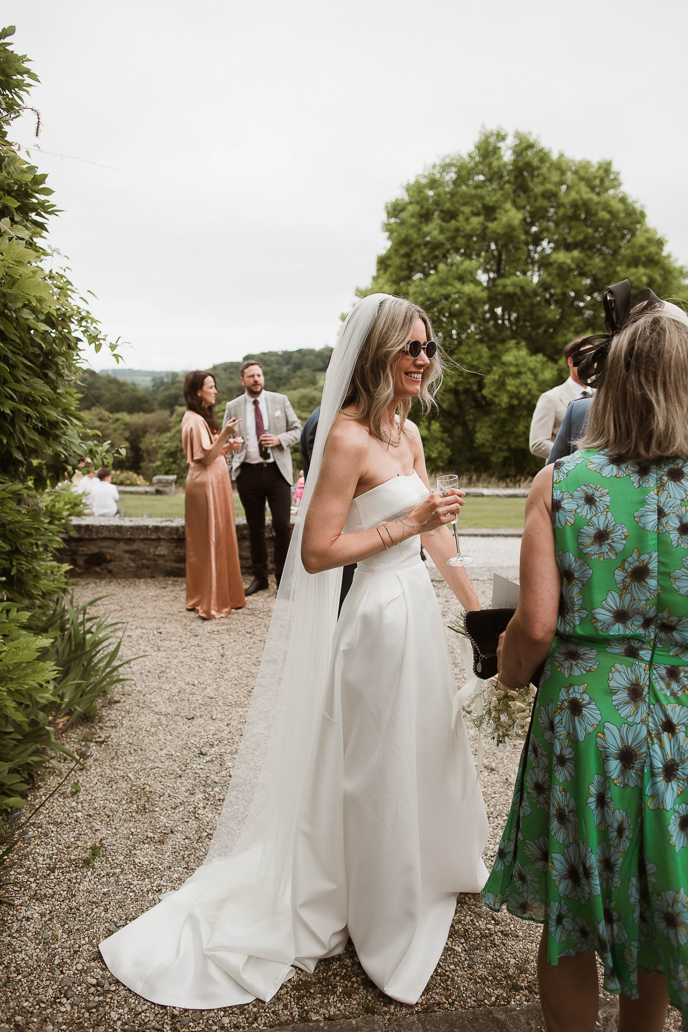 Boconnoc Estate Wedding Cornwall Jesus Peiro 102 - Lauren in Jesus Peiro for her Elegant Boconnoc Estate Wedding in Cornwall Bride wearing sunglasses with her Jesus Peiro wedding dress during the drinks reception at her wedding.