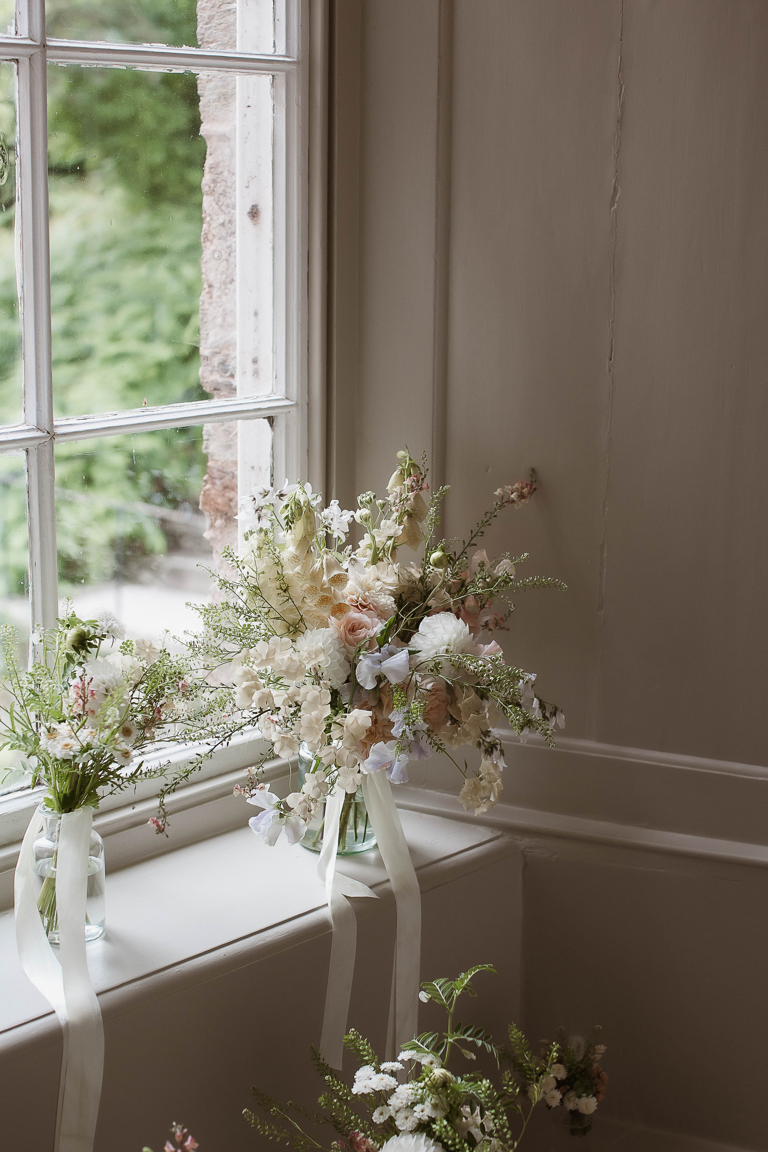 Boconnoc Estate Wedding Cornwall Jesus Peiro 17 - Lauren in Jesus Peiro for her Elegant Boconnoc Estate Wedding in Cornwall Elegant summer wedding bouquet in pale pastels sat in a glass vase on the window sill.