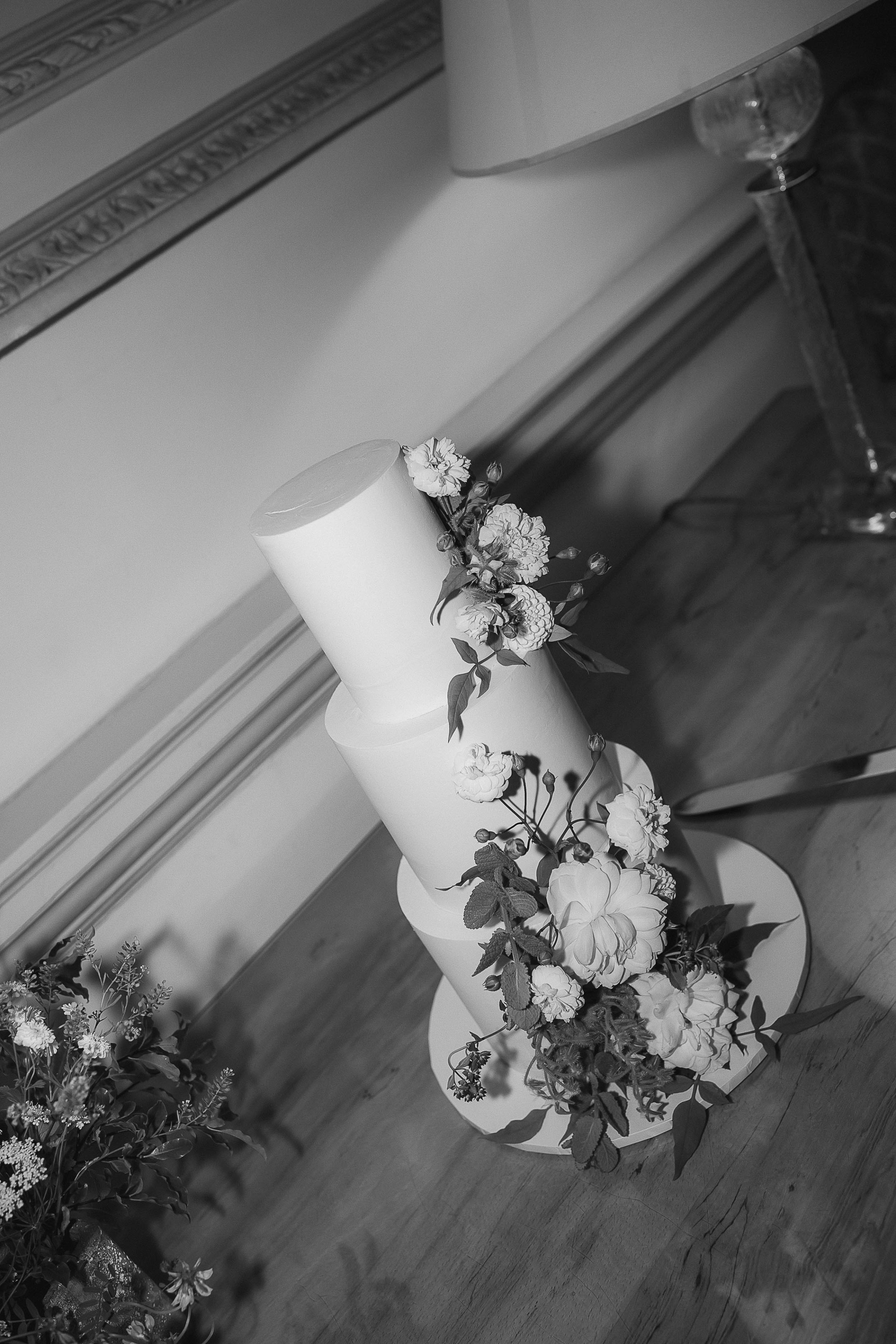 Boconnoc Estate Wedding Cornwall Jesus Peiro 173 - Lauren in Jesus Peiro for her Elegant Boconnoc Estate Wedding in Cornwall Black and white photograph of an elegant 3 tier wedding cake with flowers and foliage.
