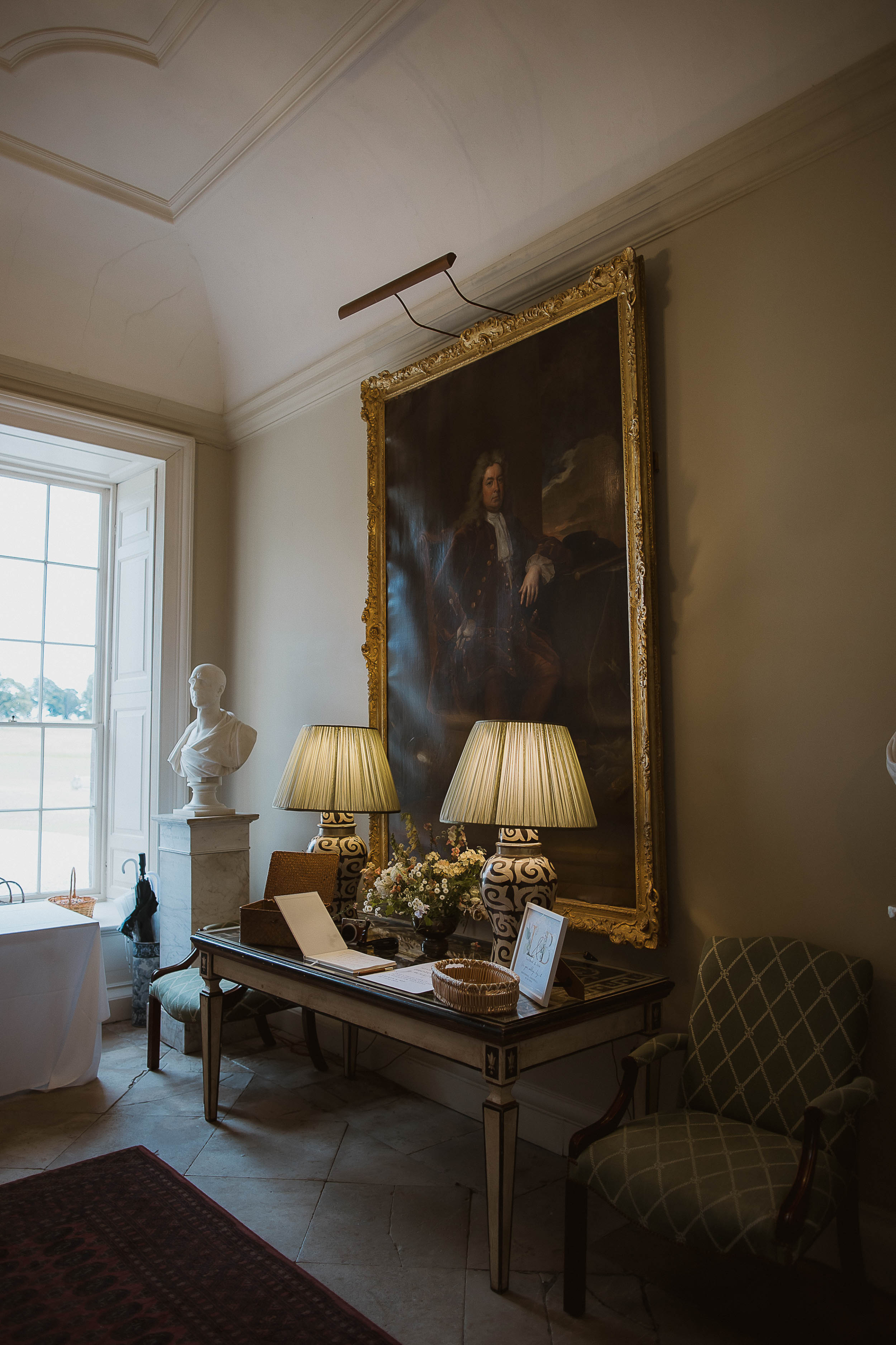 Boconnoc Estate Wedding Cornwall Jesus Peiro 6 - Lauren in Jesus Peiro for her Elegant Boconnoc Estate Wedding in Cornwall Elegant lampshades on a side table inside Boconnoc Estate wedding venue with a large historical painting hanging on the wall in the background.