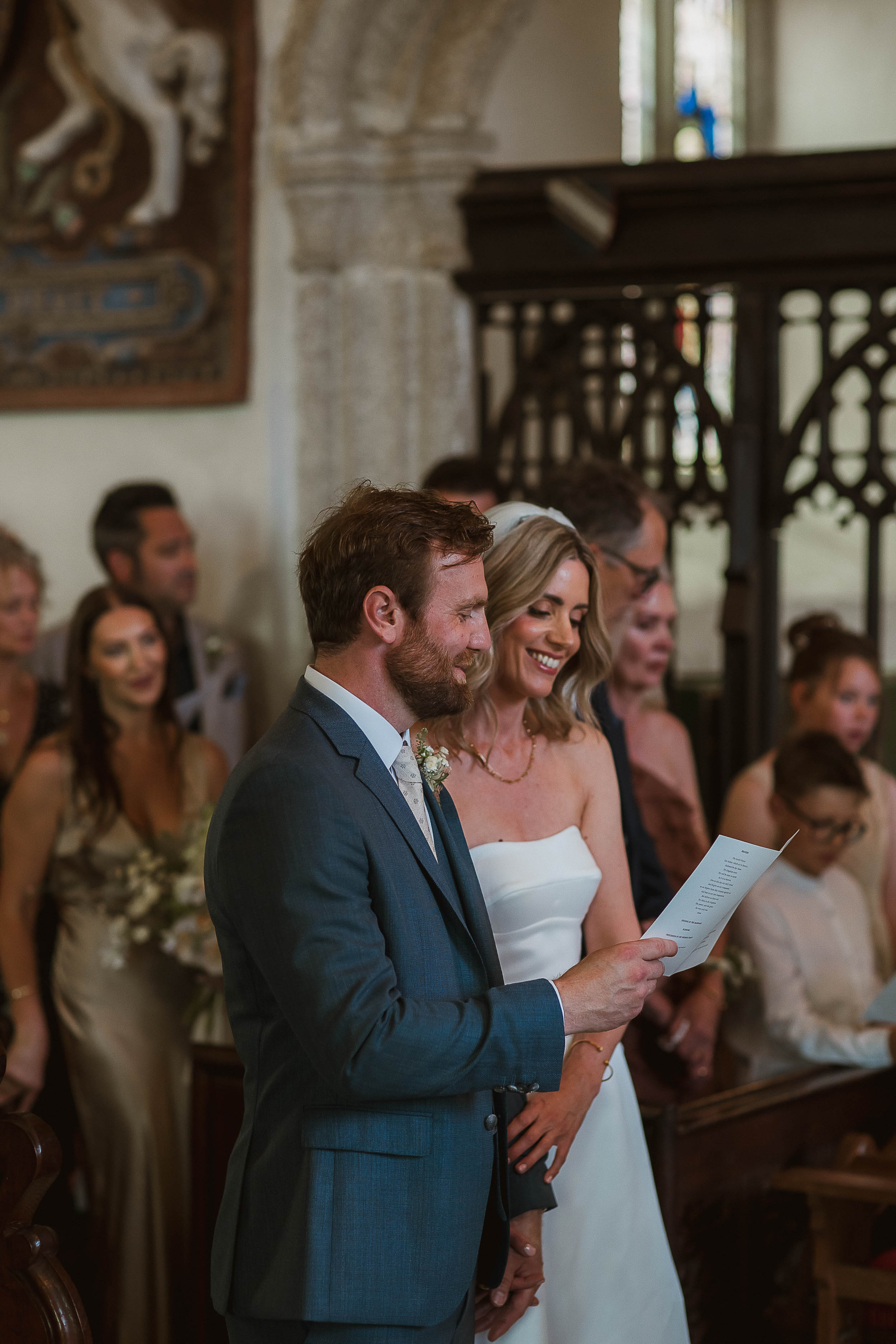 Boconnoc Estate Wedding Cornwall Jesus Peiro 65 - Lauren in Jesus Peiro for her Elegant Boconnoc Estate Wedding in Cornwall Bride and groom singing from a hymn sheet in church.