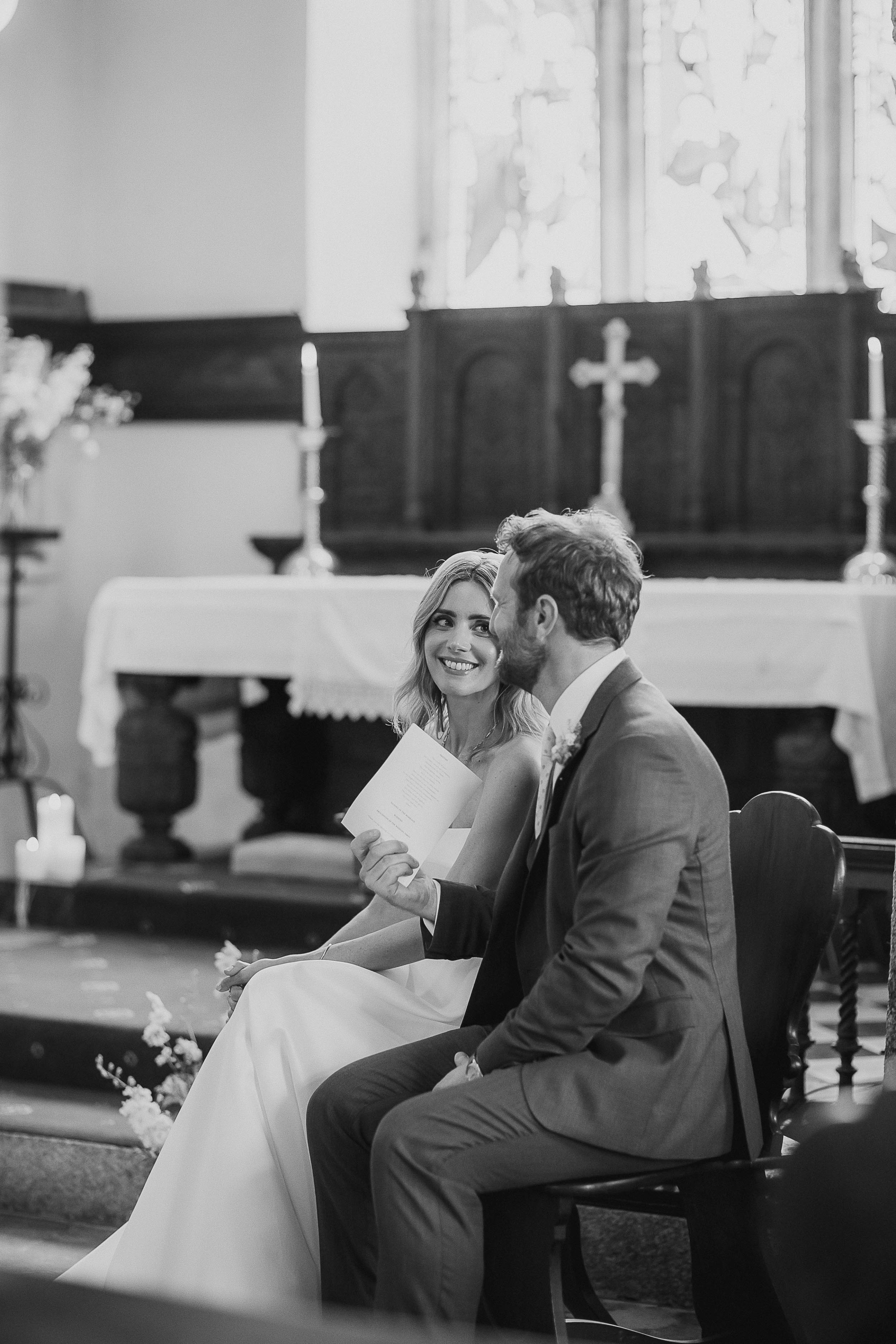 Boconnoc Estate Wedding Cornwall Jesus Peiro 66 - Lauren in Jesus Peiro for her Elegant Boconnoc Estate Wedding in Cornwall Bride and groom seated during their church ceremony and looking at one another lovingly.