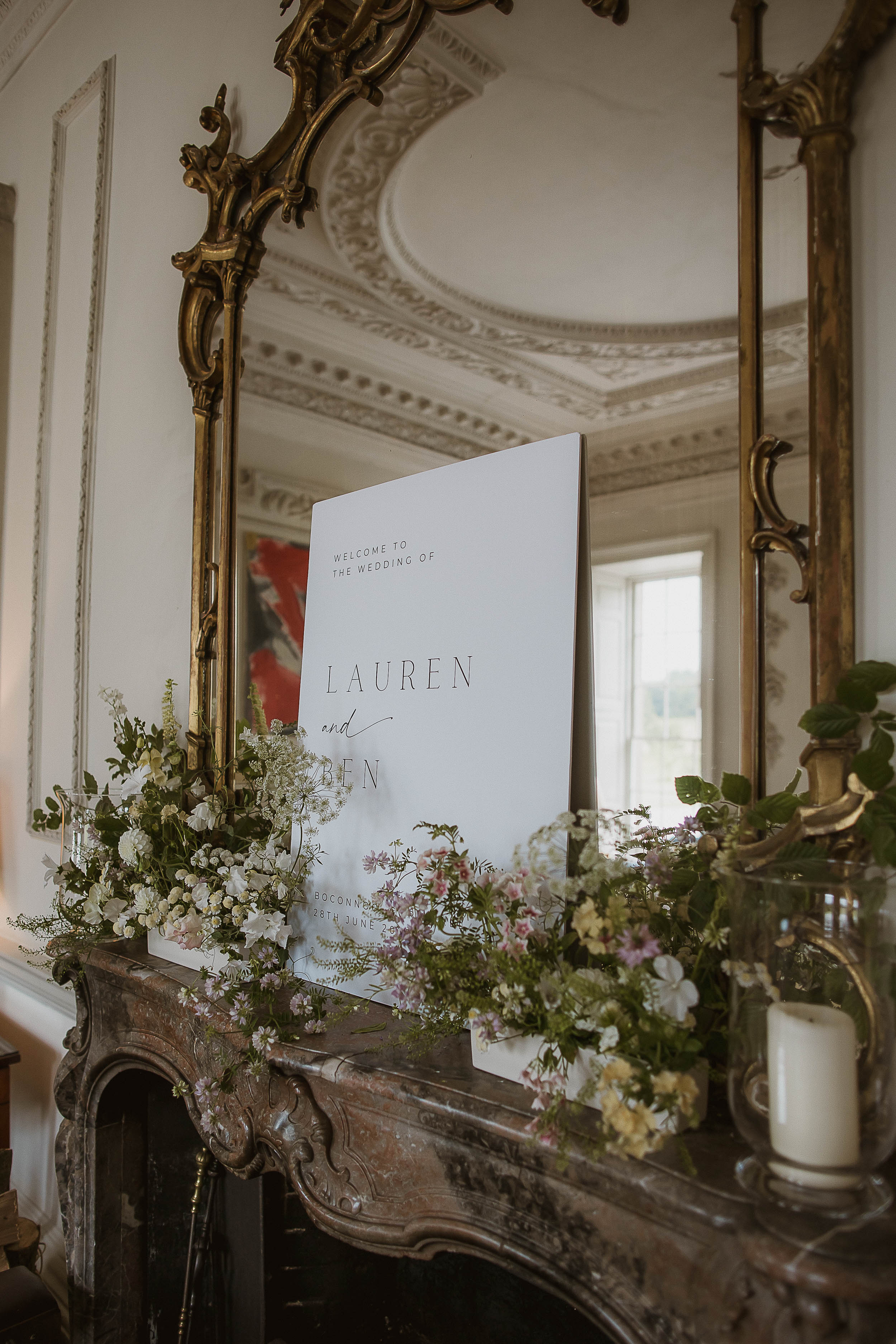 Boconnoc Estate Wedding Cornwall Jesus Peiro 8 - Lauren in Jesus Peiro for her Elegant Boconnoc Estate Wedding in Cornwall Wedding signage propped up against a mirror on a mantel piece inside Boconnoc Estate wedding venue in Cornwall.