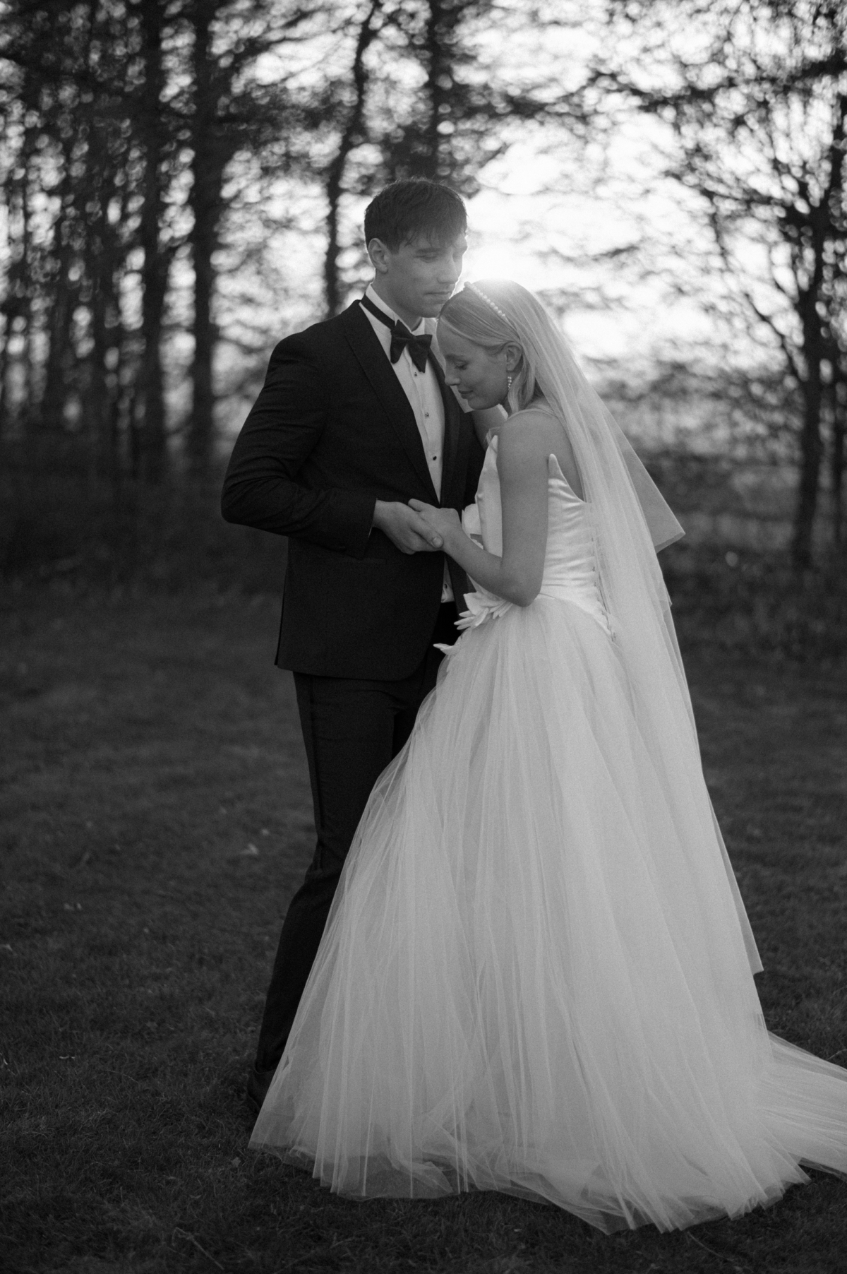 Earnshill House Wedding Editorial Fern Godfrey Weddings 27 - Modern Bridal Elegance at Earnshill House, A Romantic Somerset Wedding Venue Groom in black tie lovingly holding the hands of his bride wearing JULITA at Earnshill House, a romantic Somerset county house wedding venue.