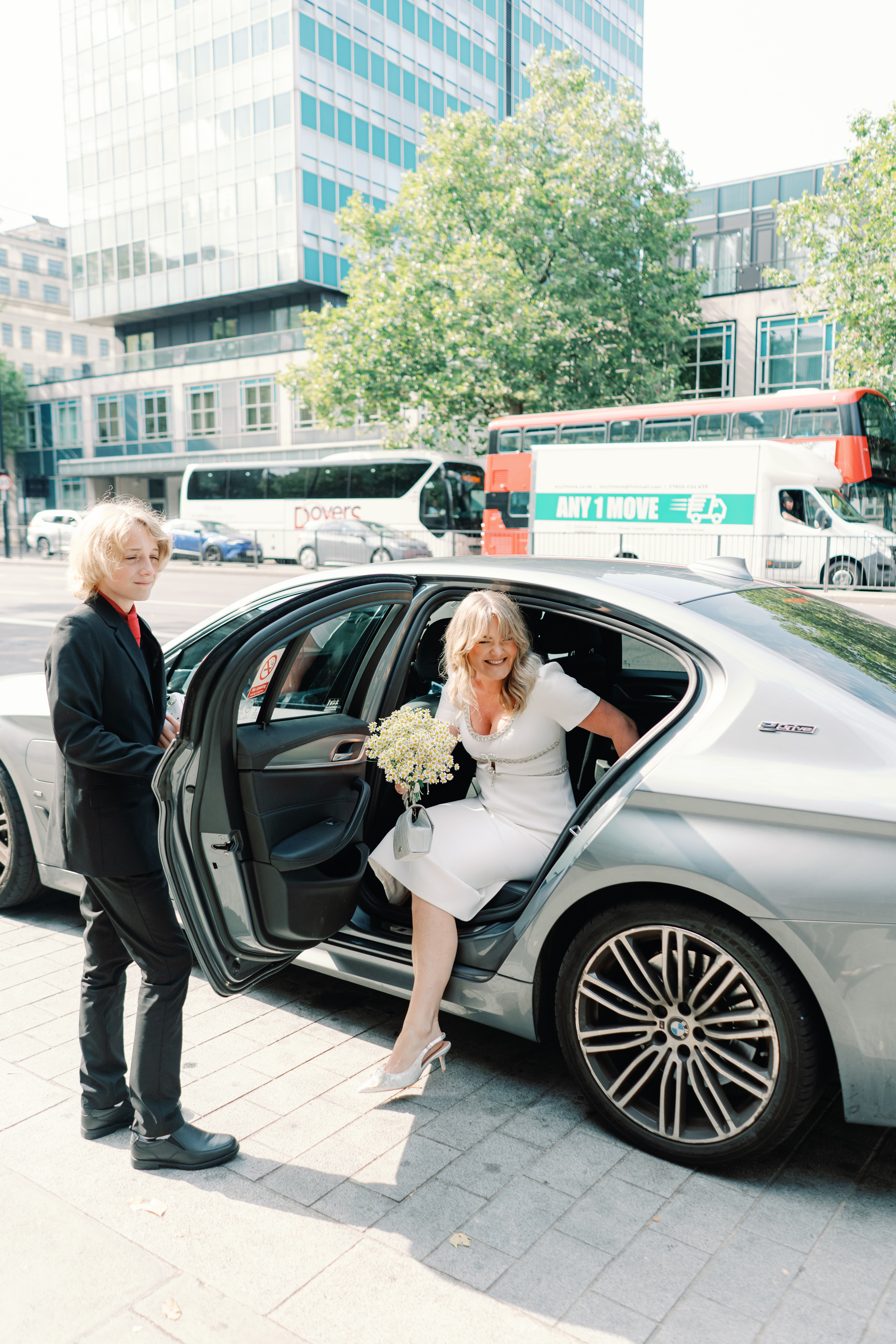 Emmylou Kelly Registry Office Wedding Jessica Lily Photography 100 - Photographer Emmylou Kelly & Paul's Intimate Family Registry Office Wedding Bride stepping out of an Uber taxi in London. Her son is holding the door open for her.