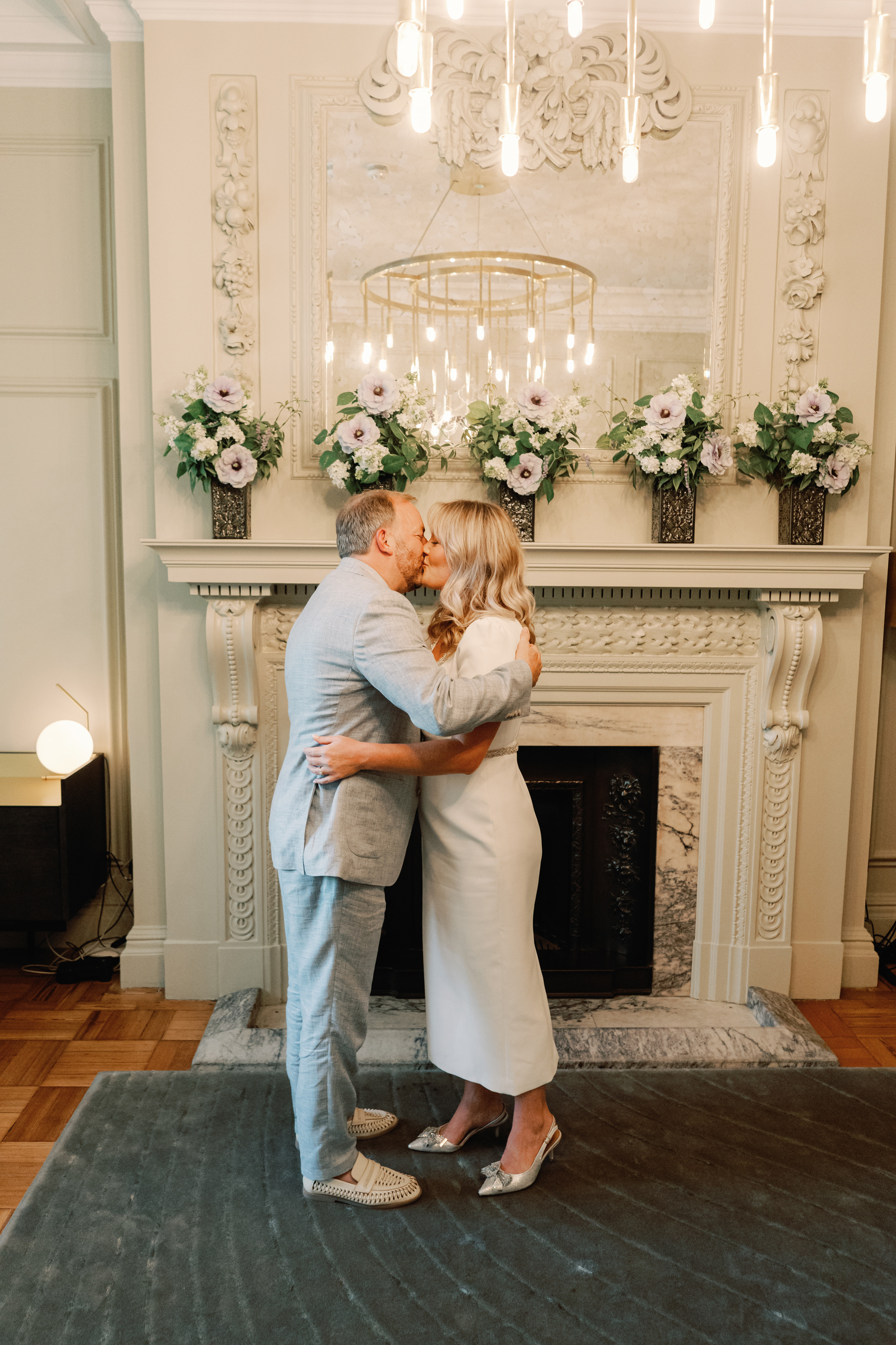 Emmylou Kelly Registry Office Wedding Jessica Lily Photography 108 - Photographer Emmylou Kelly & Paul's Intimate Family Registry Office Wedding Bride and groom kissing during their ceremony room at Old Marylebone Town Hall. She carries a small bouquet of Chamomile and wears a Self Portrait midi dress.