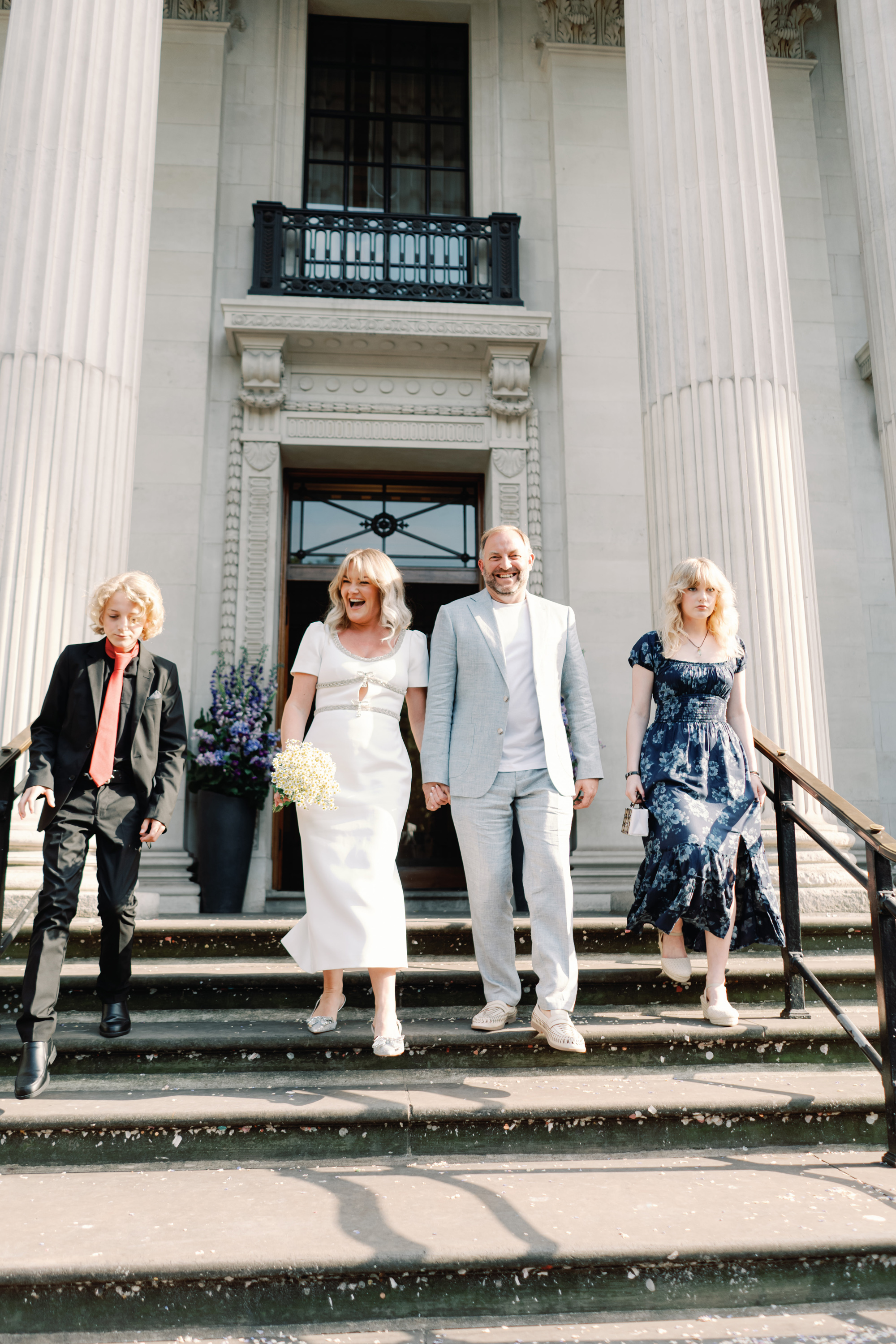 Emmylou Kelly Registry Office Wedding Jessica Lily Photography 117 - Photographer Emmylou Kelly & Paul's Intimate Family Registry Office Wedding Bride, groom and their son and daughter walking down the stairs of Old Marylebone Town Hall after their intimate family wedding.