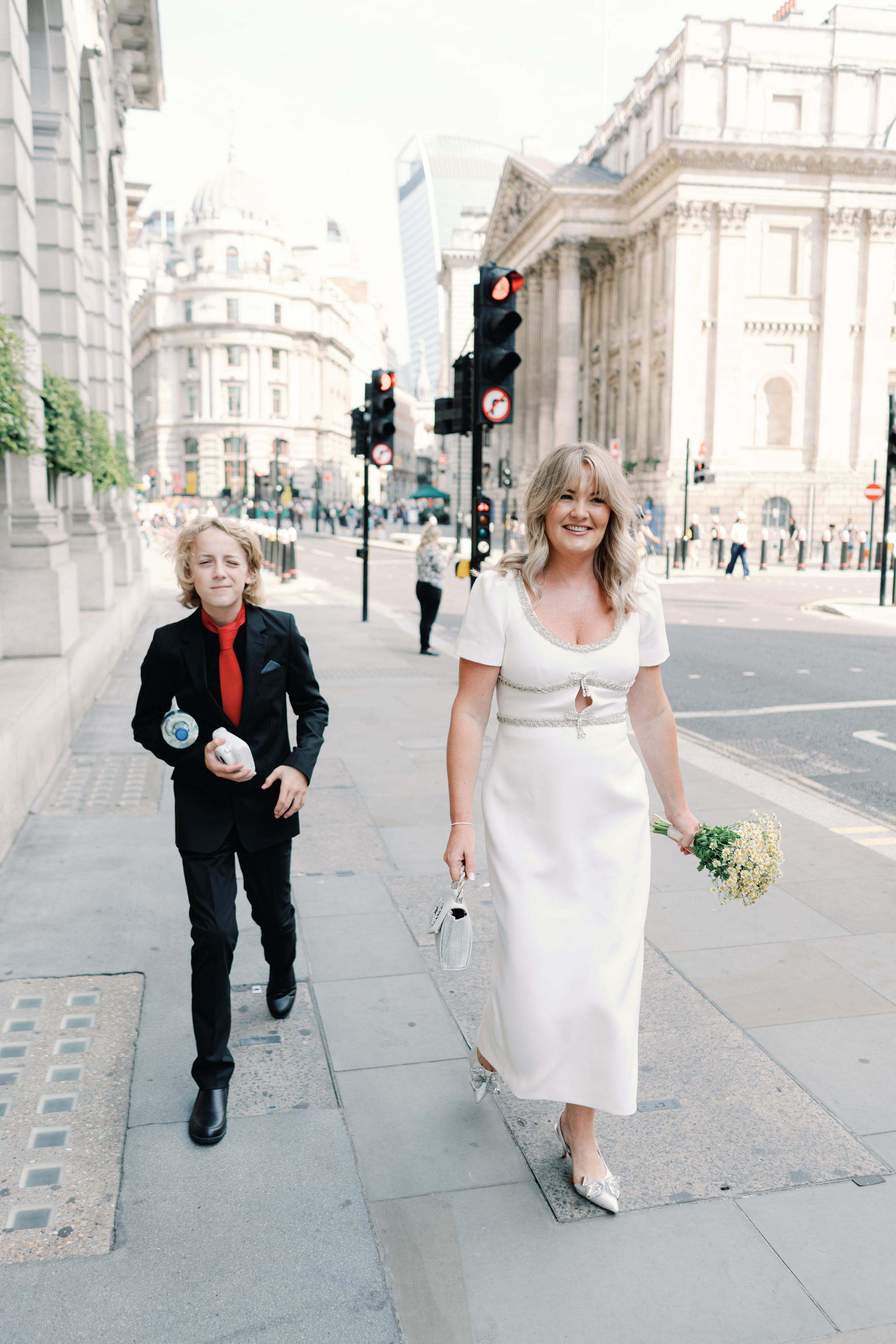 Emmylou Kelly Registry Office Wedding Jessica Lily Photography 99 - Photographer Emmylou Kelly & Paul's Intimate Family Registry Office Wedding Bride in a midi dress by Self Portrait and her son in a black trousers and shirt and a red time walking through the streets of London.