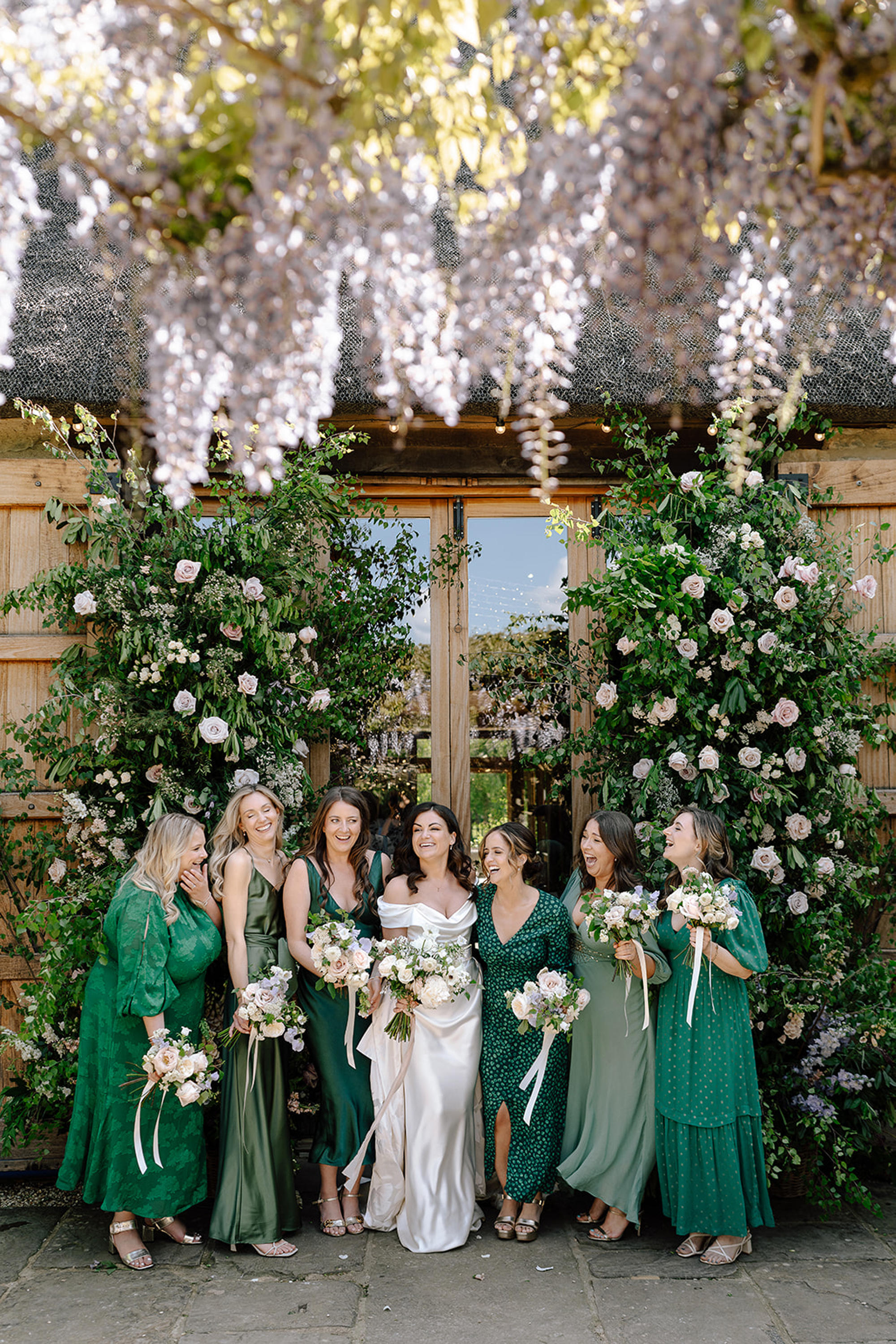 The New Wedding Aesthetic: A Sense of Home 11 Bridesmaids in green dresses in mismatched style, at Tythe, Oxfordshire barn wedding venue