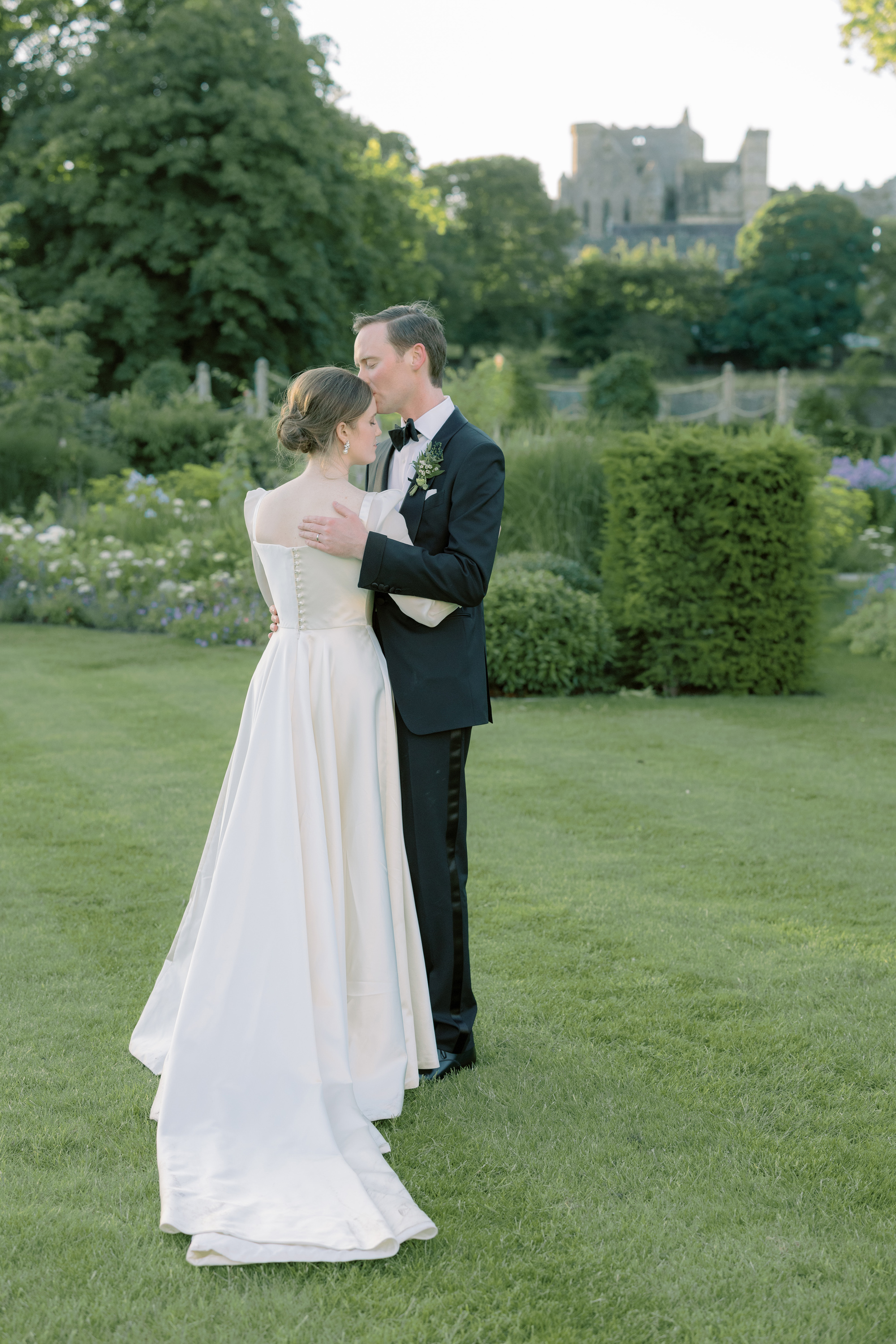 Romantic wedding photography taken in the gardens of Cashel Palace in County Tipperary, Ireland. Groom in black tie is gently embracing his bride wearing a Phillipa Lepley bridal gown with her hair in an a low messy bun.