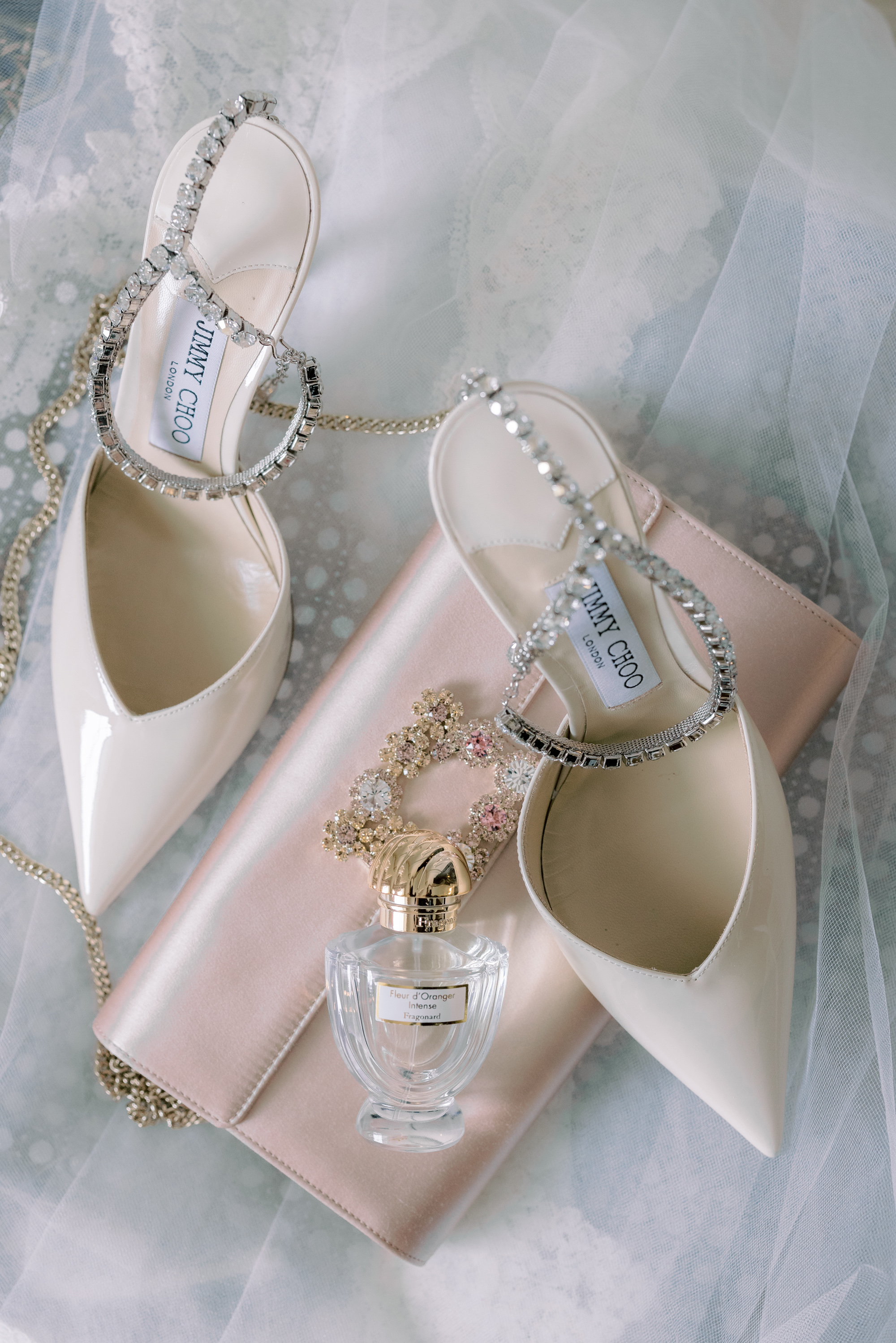 Jimmy Choo wedding shoes, flatlay with a pale pink bridal clutch by Roger Vivier.