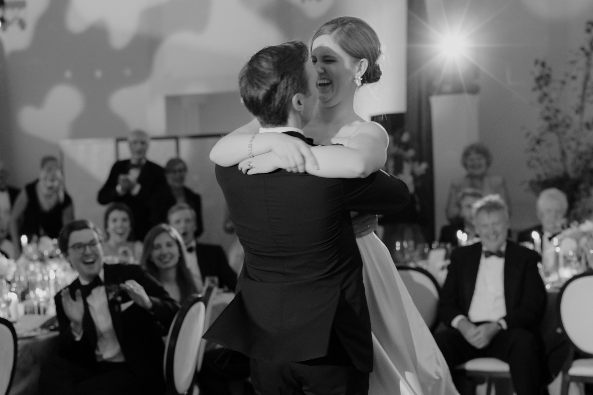 Bride laughing with glee as her groom lifts her from the dance floor.