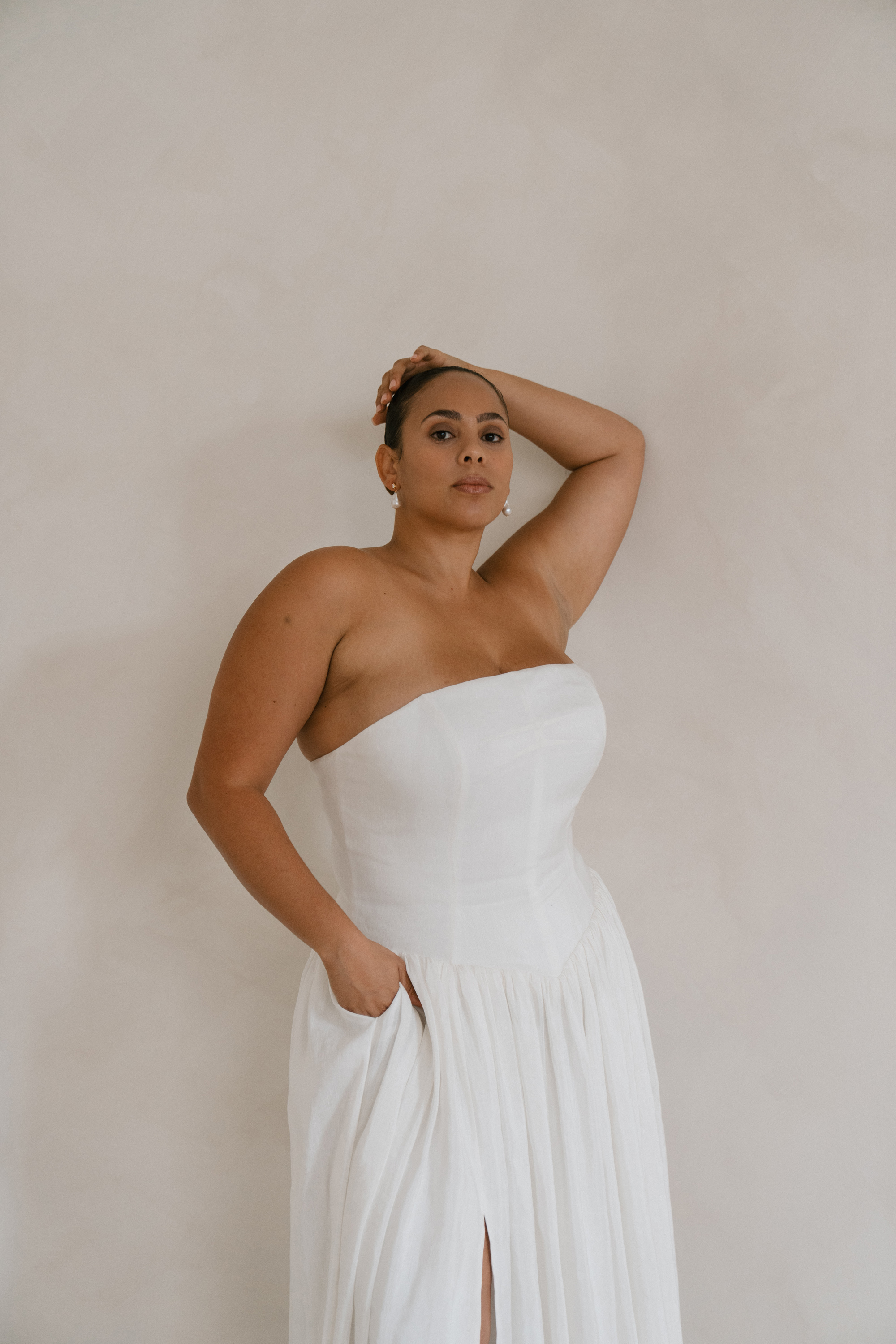 Plus size curvy Black bridal model wearing Rolling in Roses modern strapless wedding dress with pockets.