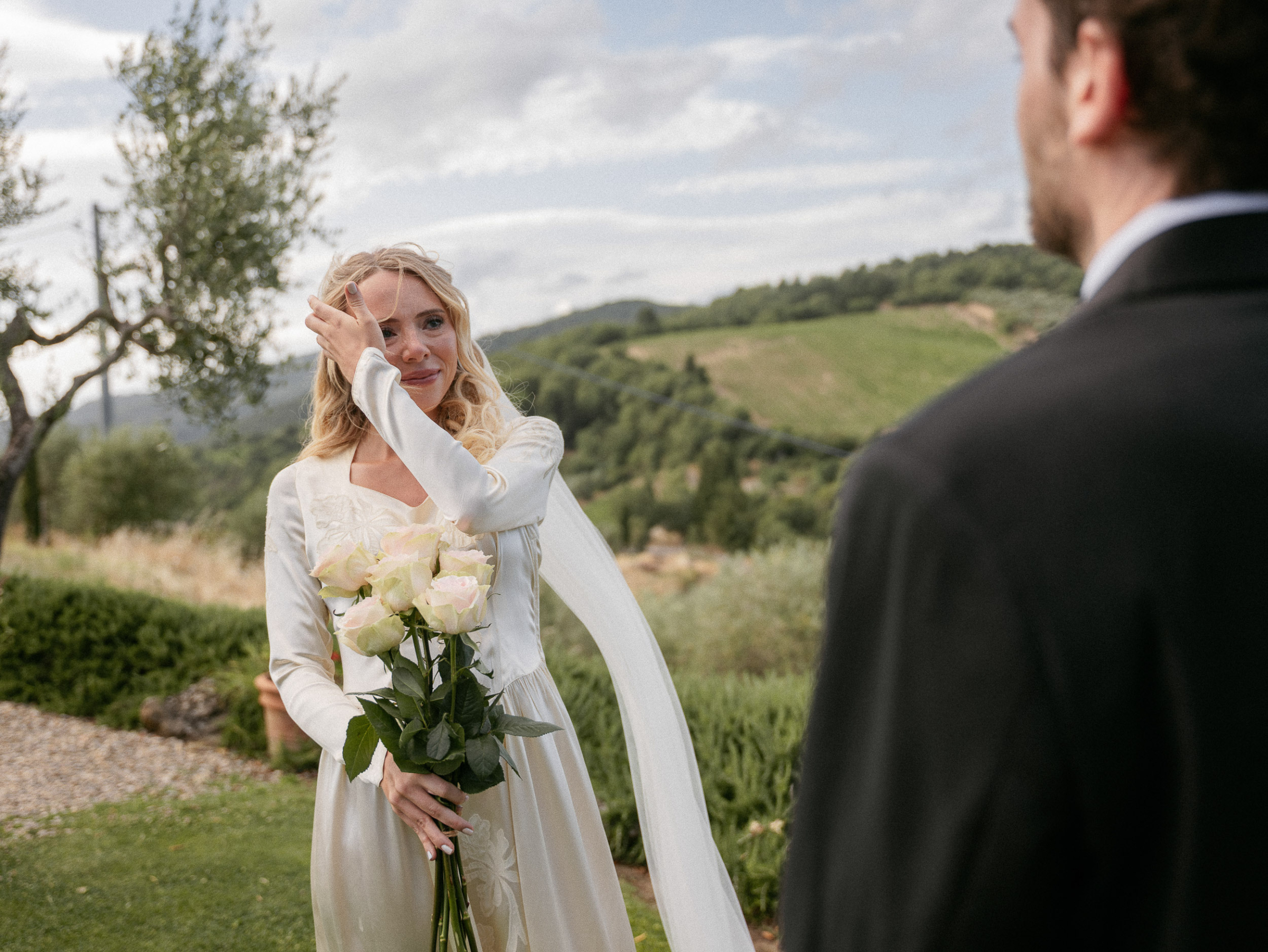 Romantic Tuscan Elopement on Film 118 - An Original 1940s Vintage Dress for Emily & Ned's Intimate Elopement in Tuscany Bride in 1940s vintage wedding dress wiping tears during her elopement ceremony in Tuscany. She carries a bouquet of large roses with long stems.