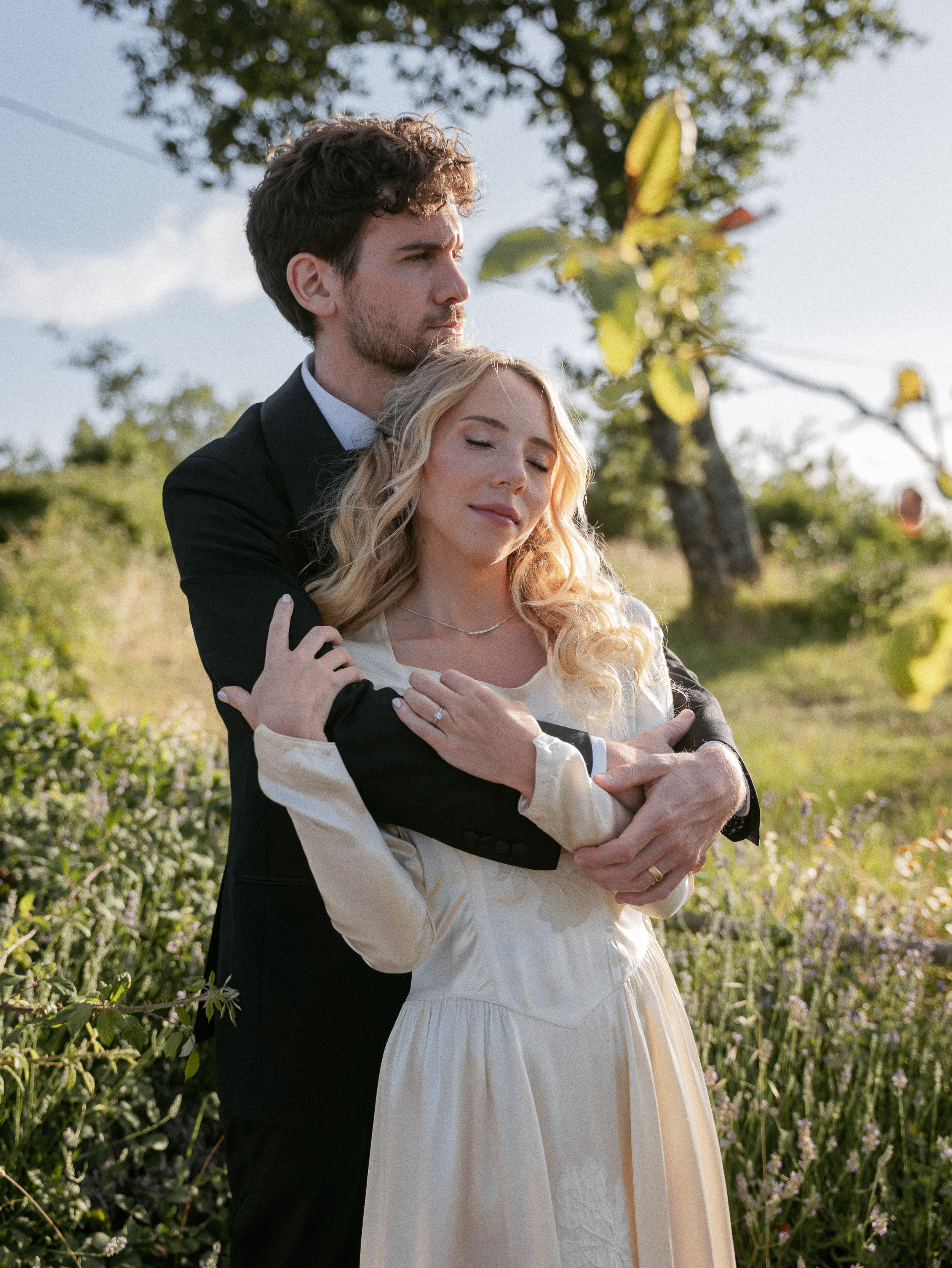 Romantic Tuscan Elopement on Film 249 - An Original 1940s Vintage Dress for Emily & Ned's Intimate Elopement in Tuscany Bride in a 1940's original silk vintage wedding dress with long pointed sleeves, being embraced from behind by her groom in black tie. Elopement in Tuscany.