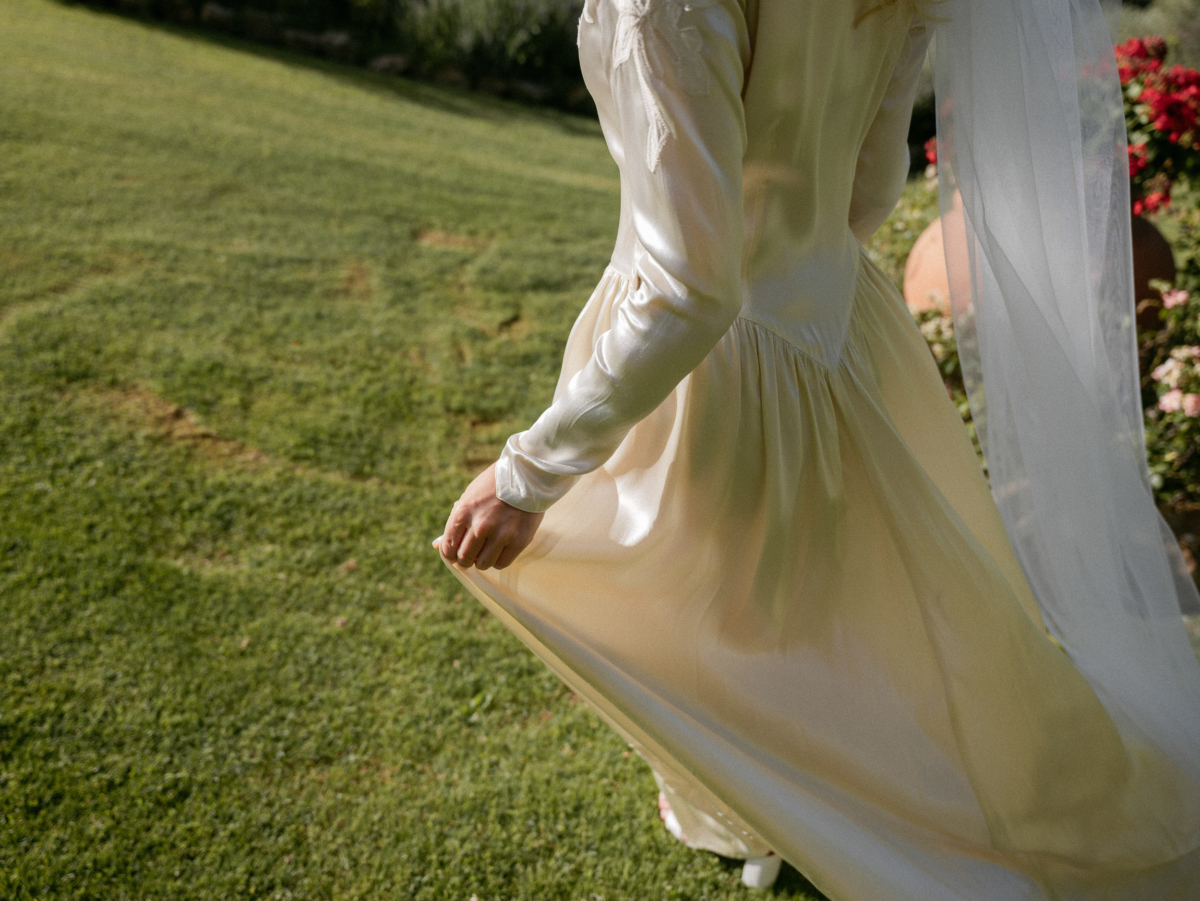 Romantic Tuscan Elopement on Film 49 - An Original 1940s Vintage Dress for Emily & Ned's Intimate Elopement in Tuscany Behind torso shot of a bride wearing a 1940's original vintage wedding dress and lifting the silk gently as she walks through gardens.
