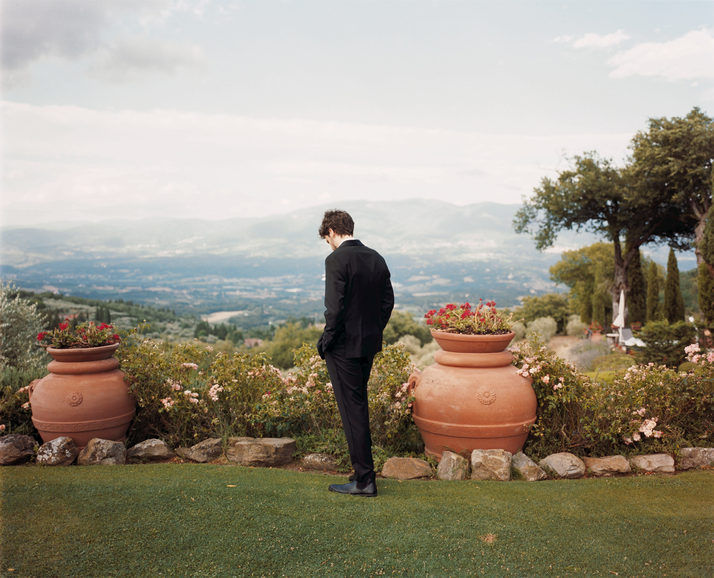 Romantic Tuscan Elopement on Film 99 - An Original 1940s Vintage Dress for Emily & Ned's Intimate Elopement in Tuscany Groom waiting for his bride to arrive at their Tuscan elopement. He is standing in a garden, the rolling hills of Tuscany in the background.