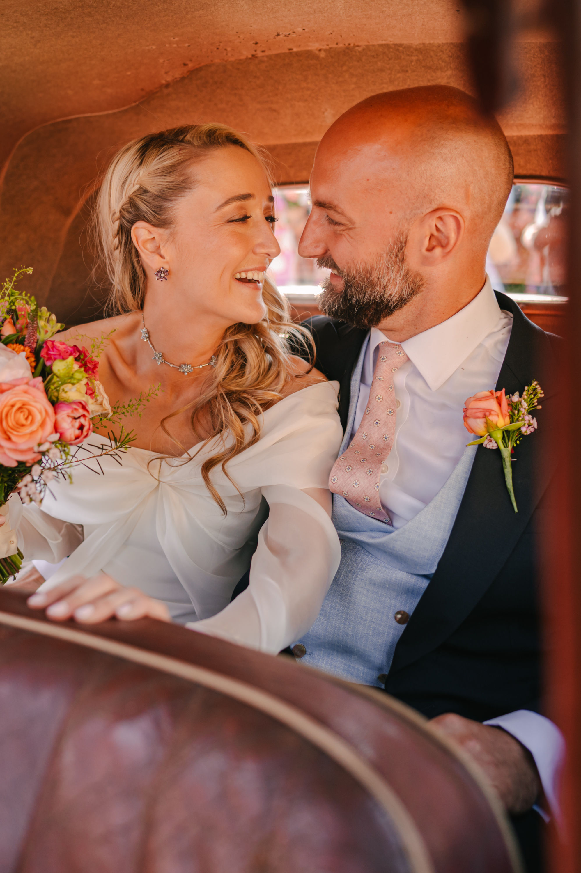 Intimate closeup shot of bride and groom cosying up in the back of a taxi on their wedding day. Sidey Clark Photography.