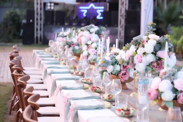 Alt Text: Wedding dinner table with pink and white floral centrepieces sage green napkins and gold accents at outdoor venue in Antalya Turkey by Ramarossi