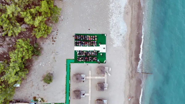 Aerial drone view of custom ceremony platform for 180 guests on Mediterranean beach with turquoise sea in Antalya Turkey by Ramarossi