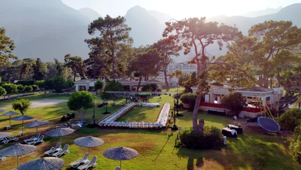 Aerial view of rehearsal dinner setup for 200 guests with U-shaped long tables and fairy light canopy on garden lawn with Taurus Mountains in Antalya Turkey by Ramarossi