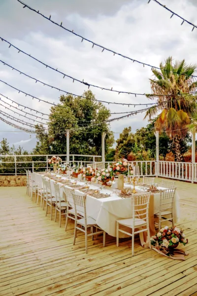 Elegant wedding table setup with white chiavari chairs and floral arrangements on terrace deck in Antalya Turkey by Ramarossi