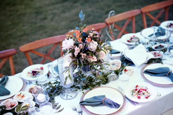 Wedding table setting with dusty blue napkins floral centrepiece and crossback chairs at destination wedding in Antalya Turkey by Ramarossi