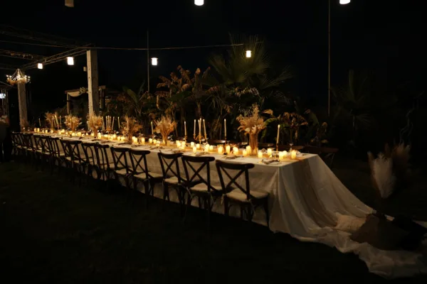 Long candlelit wedding dinner table with dried flower centrepieces pampas grass and crossback chairs at night in Antalya Turkey by Ramarossi