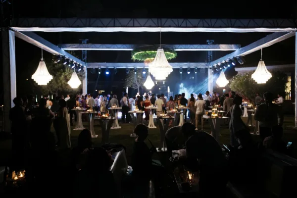 Wide view of henna night celebration with crystal chandeliers stage lighting cocktail tables and guests at outdoor venue in Antalya Turkey by Ramarossi