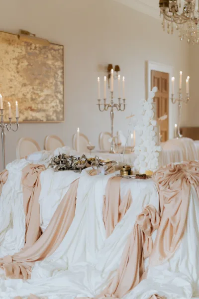 Elegant wedding reception styling at Forcett Hall in North Yorkshire featuring draped ivory and peach linens, candlelight and luxury tablescape details, photographed by Cleo Stella Photography.