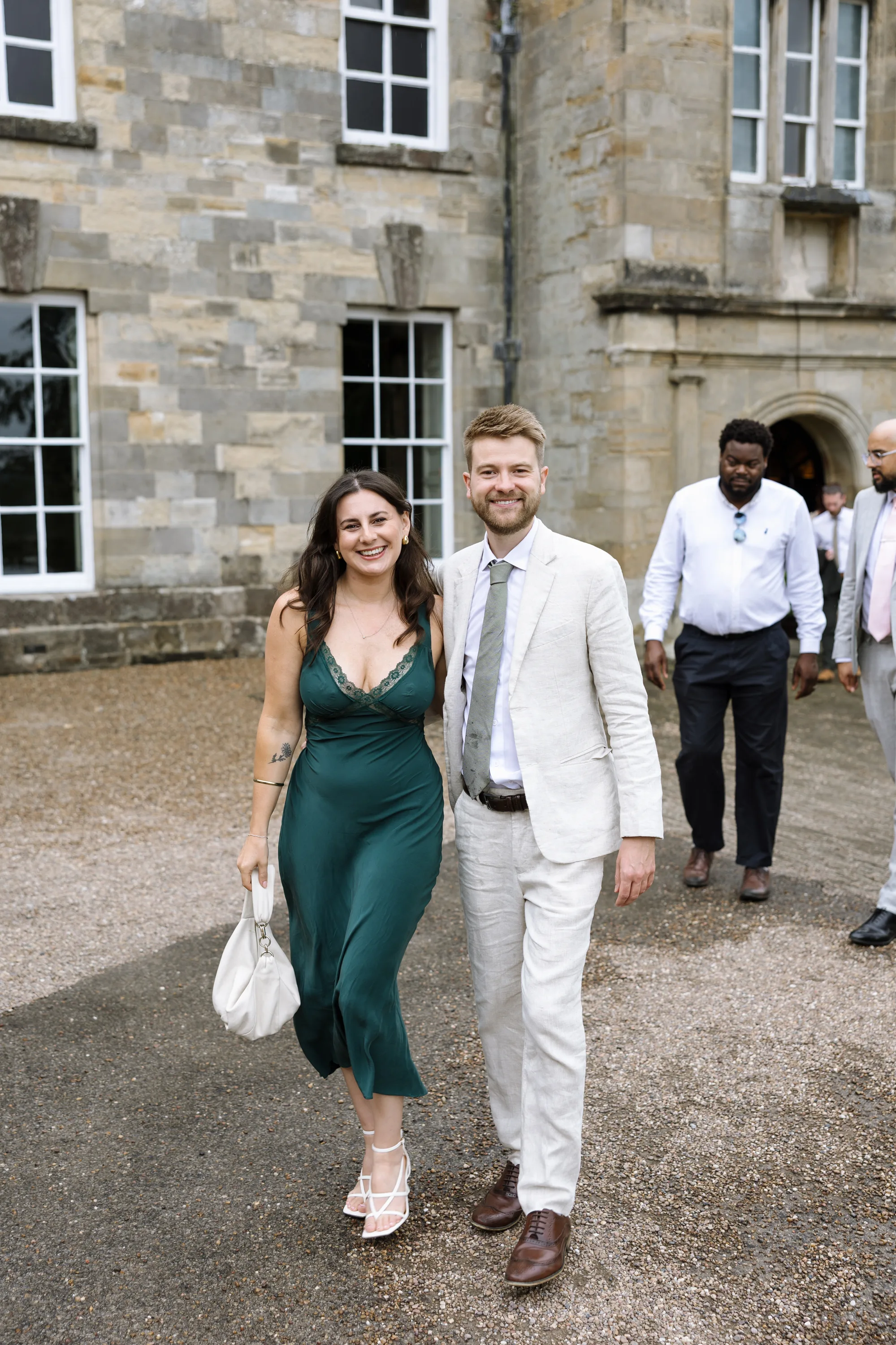 Fusion HIndu Wedding Newburgh Priory 54 - Hema & Will's Fusion Wedding & Hindu Ceremony at Newburgh Priory Elegant wedding guests in a green satin and lace dress with her partner in a light suit.