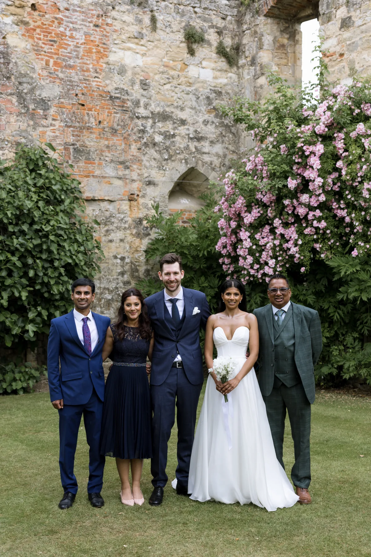 Fusion HIndu Wedding Newburgh Priory 65 1 - Hema & Will's Fusion Wedding & Hindu Ceremony at Newburgh Priory Family portrait during a wedding at Newburgh Priory. The bride wears Suzanne Neville and her bridesmaids and groom wear navy blue.