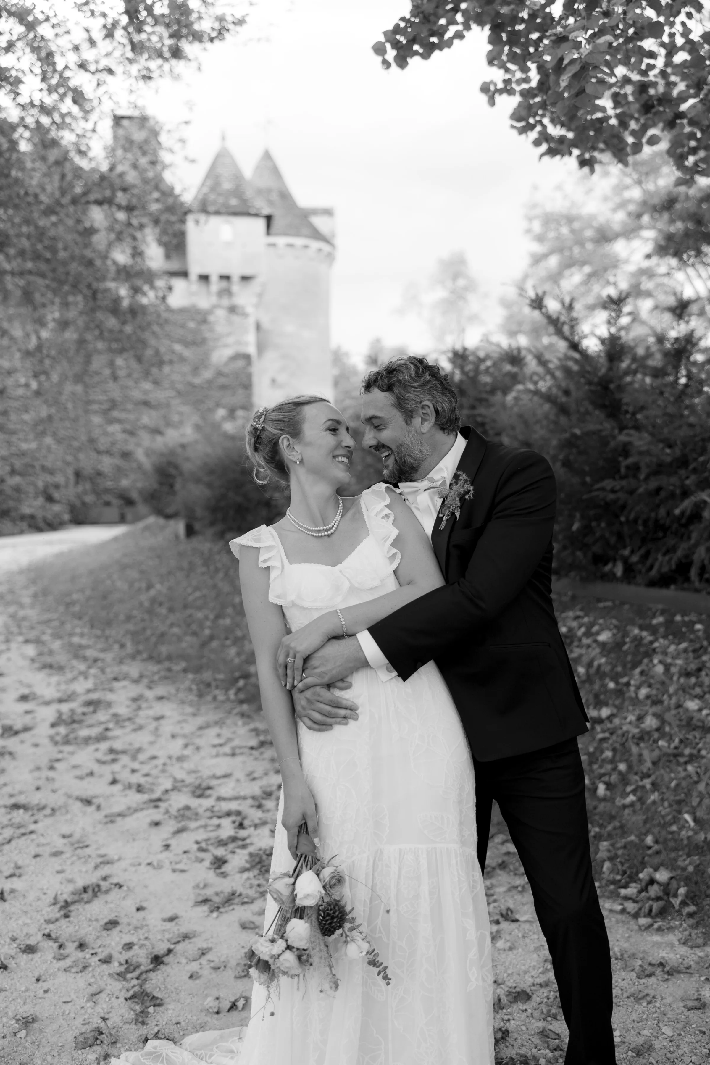Indie Bride London Chateau Cazenac wedding France 158 - Laura & Ben's Romantic & Intimate Wedding Day Gathering at Chateau Cazenac in The Dordogne Romantic black and white shot of bride and groom posting for a photograph whilst looking into one another's eyes. The from is leaning slightly into the bride as she leans slightly back. Behind them, Chateau Cazenac in the background.