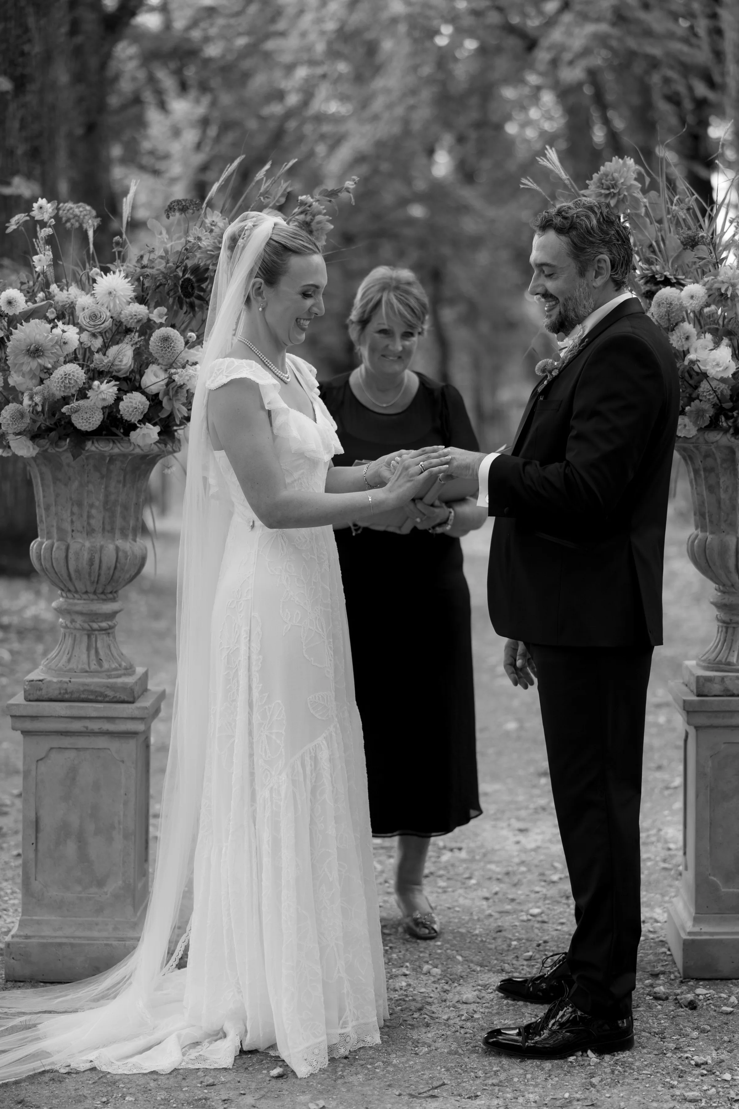 Indie Bride London Chateau Cazenac wedding France 62 1 - Laura & Ben's Romantic & Intimate Wedding Day Gathering at Chateau Cazenac in The Dordogne Bride and groom holding hands and exchanging vows during their outdoor wedding ceremony at Chateau Cazenac in the Dordogne, France. Behind then their wedding celebrant is standing smiling.