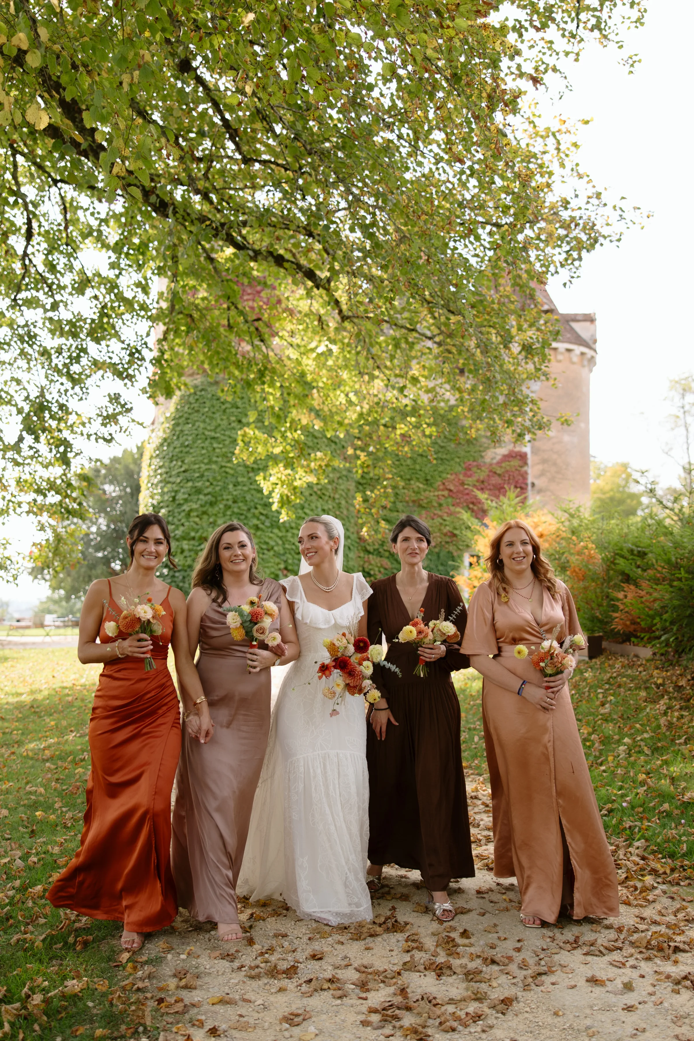 Indie Bride London Chateau Cazenac wedding France 81 - Laura & Ben's Romantic & Intimate Wedding Day Gathering at Chateau Cazenac in The Dordogne Bride wanting the grounds of Chateau Cazenac in France with her bridesmaids, who wear dresses in Autumnal shades. They are all carrying bouquets of Autumn flowers.