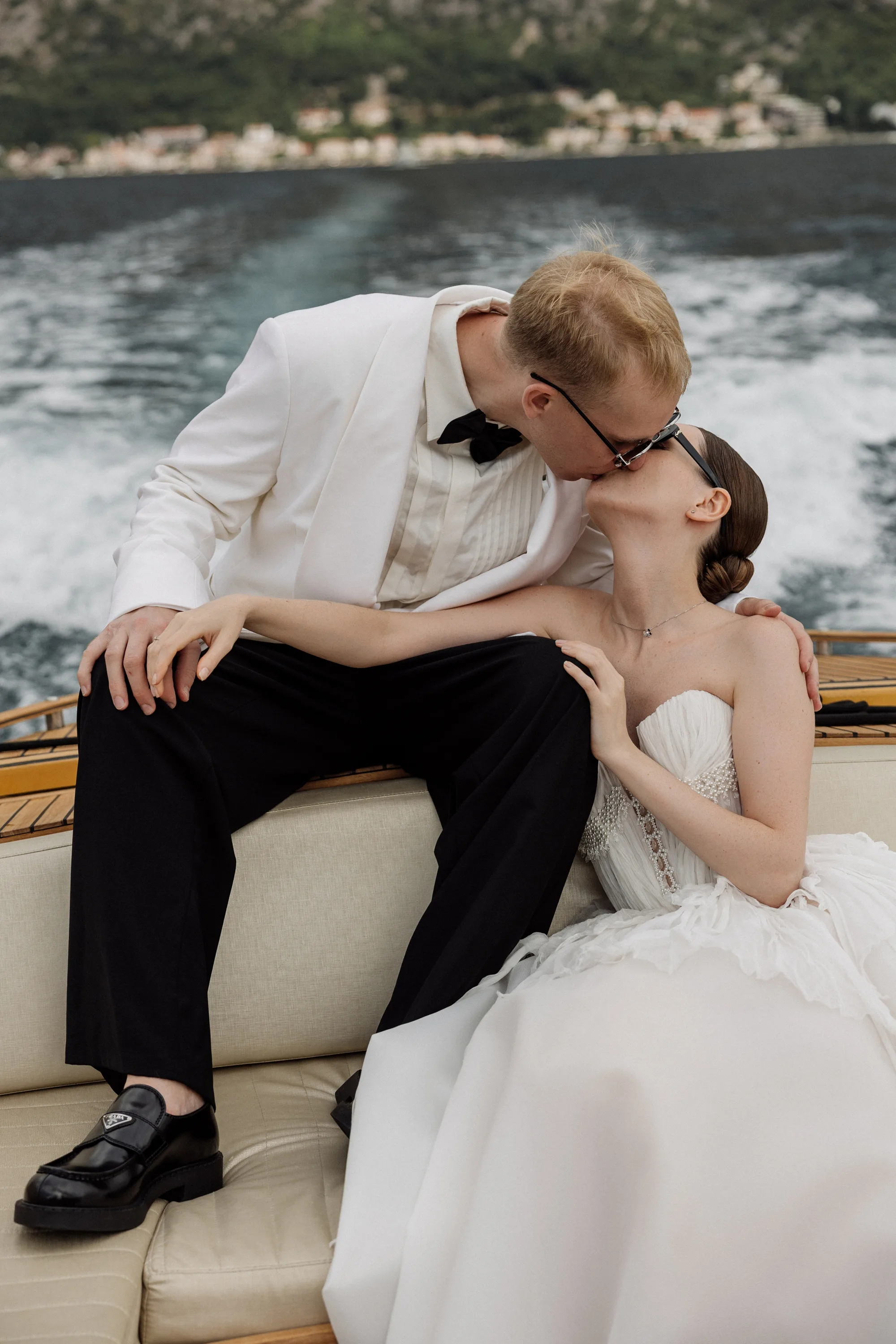 Montenegro Wedding 31 - A Romantic & Intimate Montenegro Wedding at Villa Shah, Inspired by 'La Vita Nobile' Portraits of a bride and groom on a speedboat in Montenegro. Groom wears a white tuxedo jacket and black bow tie. The bride wears a Rara Couture gown with compressed silk corset detail.