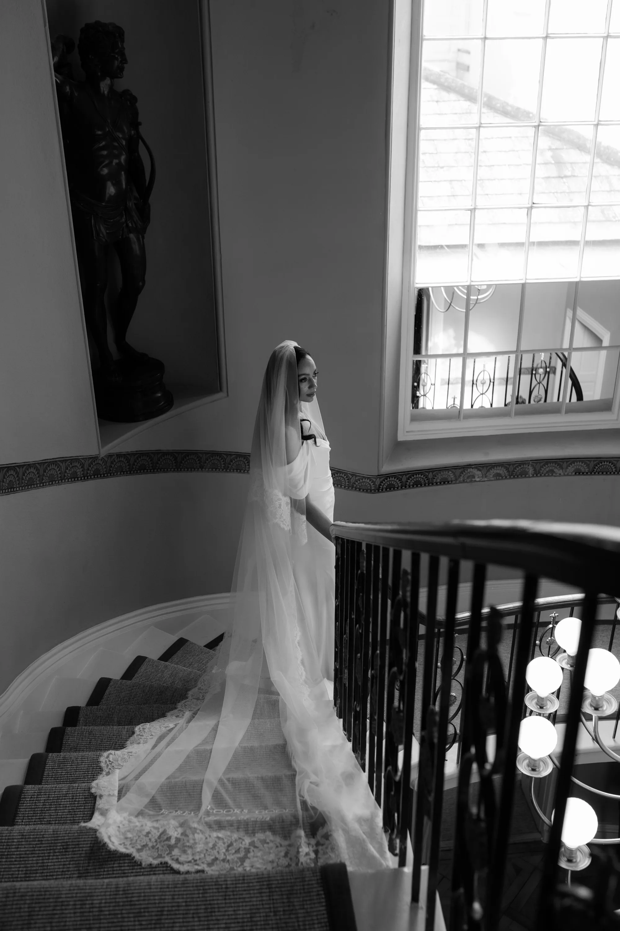 Rebecca Anne Designs embroidered wedding veils 38 - Introducing the New Embroidered Wedding Veil & Bridal Accessories Collection by Rebecca Anne Designs Black bride wearing an elegant chapel length veil featuring embroidery by Rebecca Anne Designs. She stands mid way up a sweeping staircase and the mantilla lace edged veil drapes over the stairs.