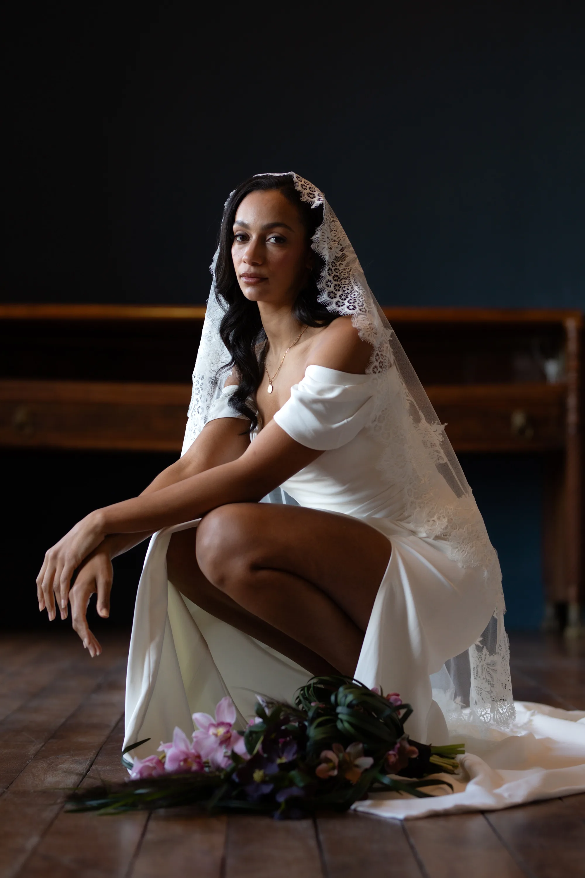 Rebecca Anne Designs embroidered wedding veils 58 1 - Introducing the New Embroidered Wedding Veil & Bridal Accessories Collection by Rebecca Anne Designs Black model bride kneeling down next to a bouquet of pink flowers. She wears an embroidered lace wedding veil. byRebecca Anne Designs.