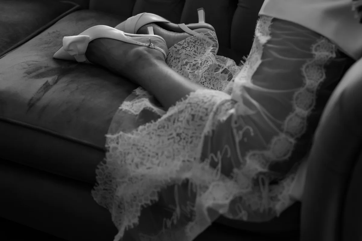 Rebecca Anne Designs embroidered wedding veils 72 2 - Introducing the New Embroidered Wedding Veil & Bridal Accessories Collection by Rebecca Anne Designs Close up shot of the legs of a bride up on a sofa. She wears white bow slingbacks and an her dress features a tulle panel that has been embroidered by Rebecca Anne Designs.