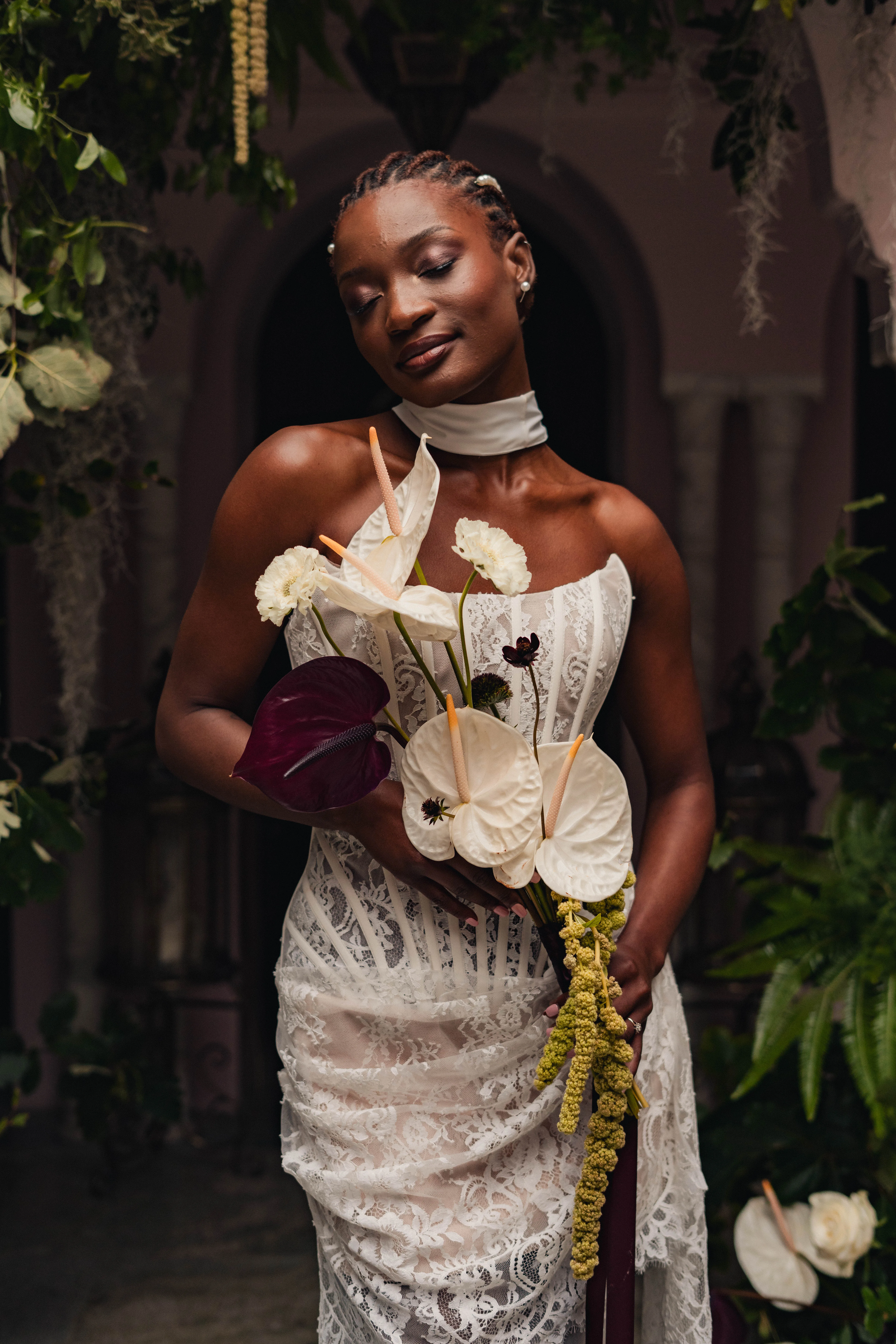 SS Port Lympne Safari Park New Orleans Wedding Editorial The Chamberlins Film Medium Format Photography London Surrey 273 - Wedding Inspiration That Celebrates The Joy, Diversity & Vibrancy of New Orleans Black model bride wears a modern corseted lace wedding dress and carries a bouquet with large white orchids. Her hair is braided and decorated with pearls.