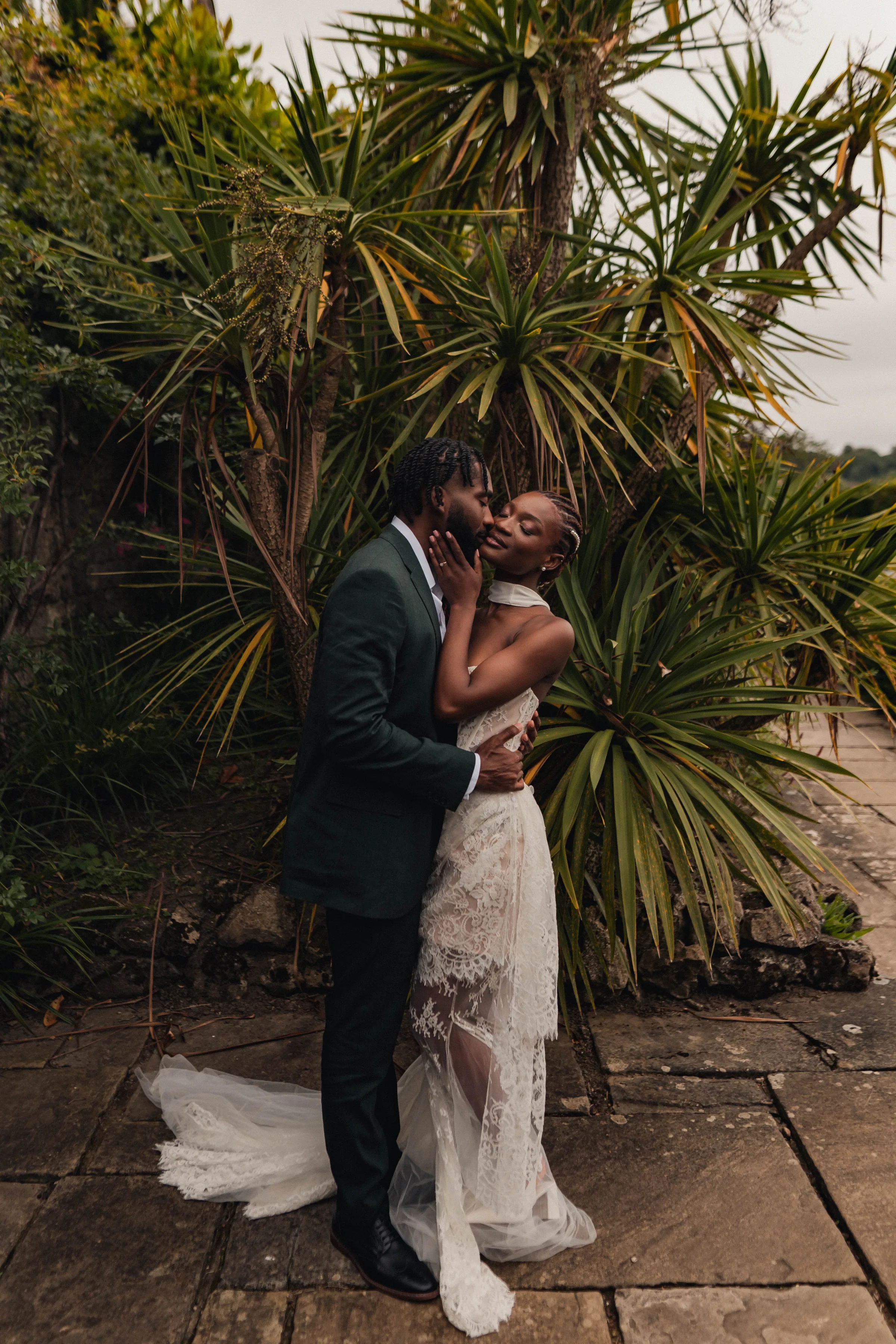 SS Port Lympne Safari Park New Orleans Wedding Editorial The Chamberlins Film Medium Format Photography London Surrey 601 - Wedding Inspiration That Celebrates The Joy, Diversity & Vibrancy of New Orleans Black bride and groom standing beside palms and embracing one another.