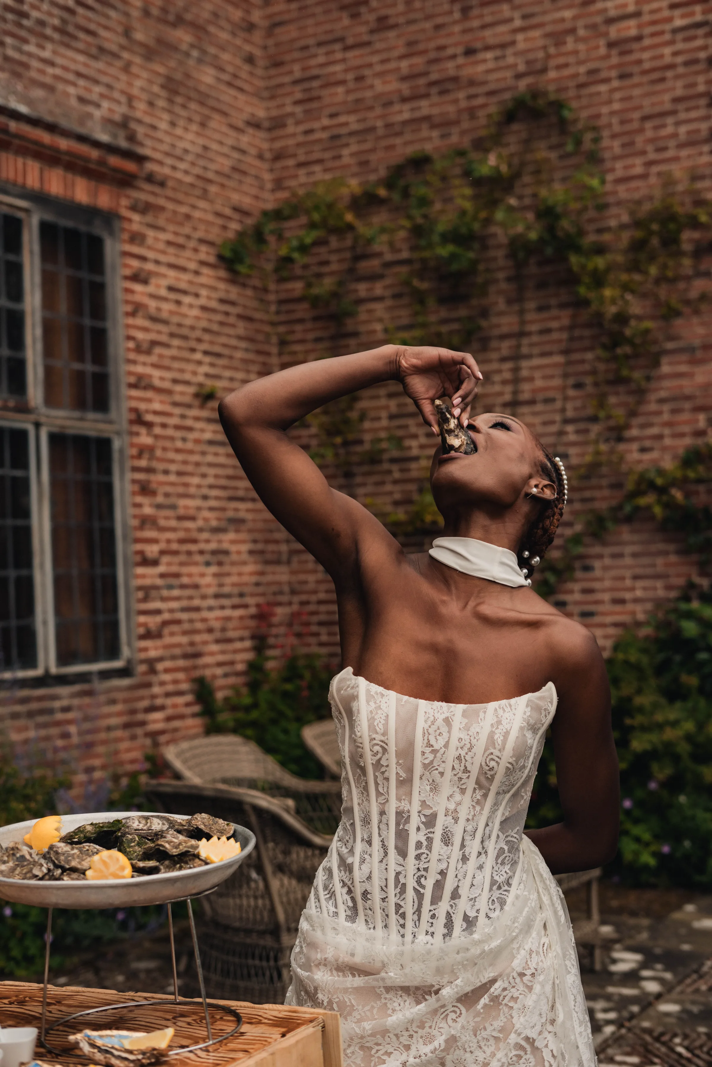 SS Port Lympne Safari Park New Orleans Wedding Editorial The Chamberlins Film Medium Format Photography London Surrey 648 - Wedding Inspiration That Celebrates The Joy, Diversity & Vibrancy of New Orleans Black bride in a modern corseted dress tipping her head back to enjoy an oyster.