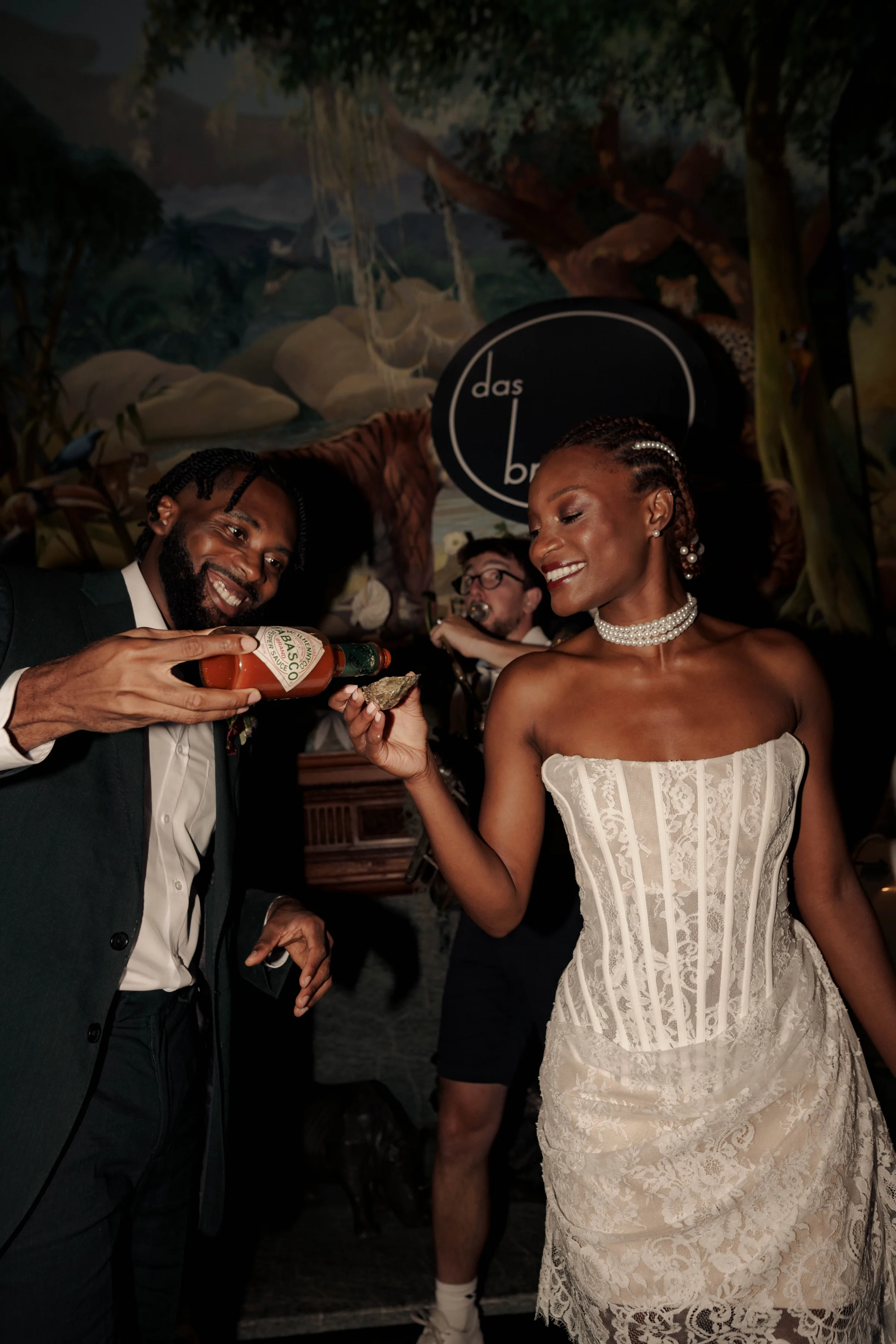 SS Port Lympne Safari Park New Orleans Wedding Editorial The Chamberlins Film Medium Format Photography London Surrey 725 - Wedding Inspiration That Celebrates The Joy, Diversity & Vibrancy of New Orleans Black bride and groom enjoying oysters and Tobasco sauce. Behind them a live brass brand are playing.
