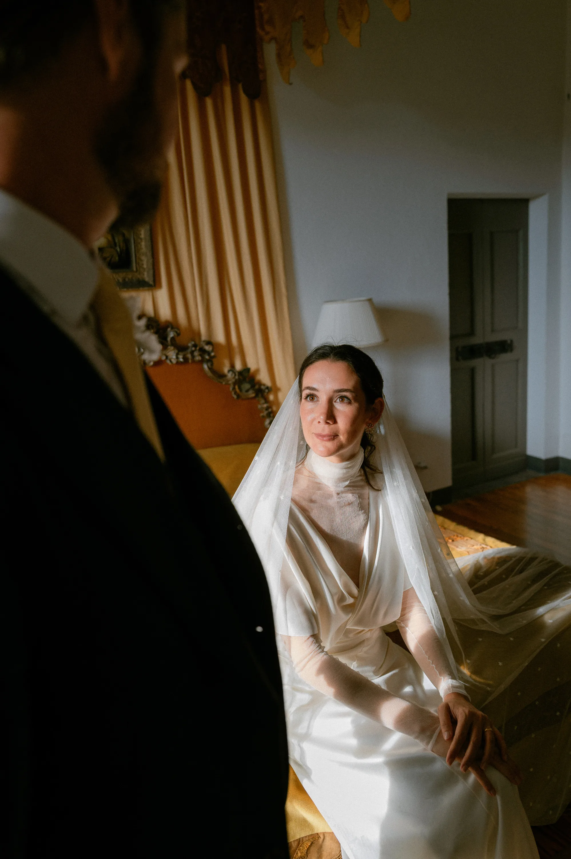 Bride wearing a Cortana wedding dress and veil with tiny embroidered stars looking up towards her groom.