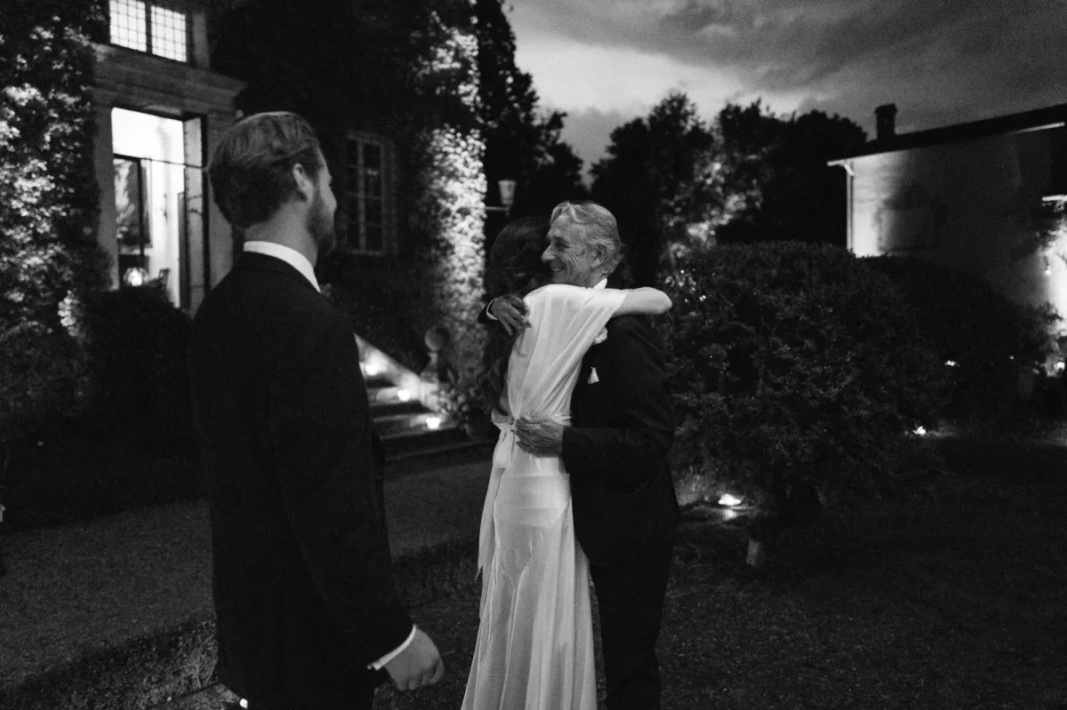 Moving black and white portrait of a bride wearing Cortana hugging her father closely.