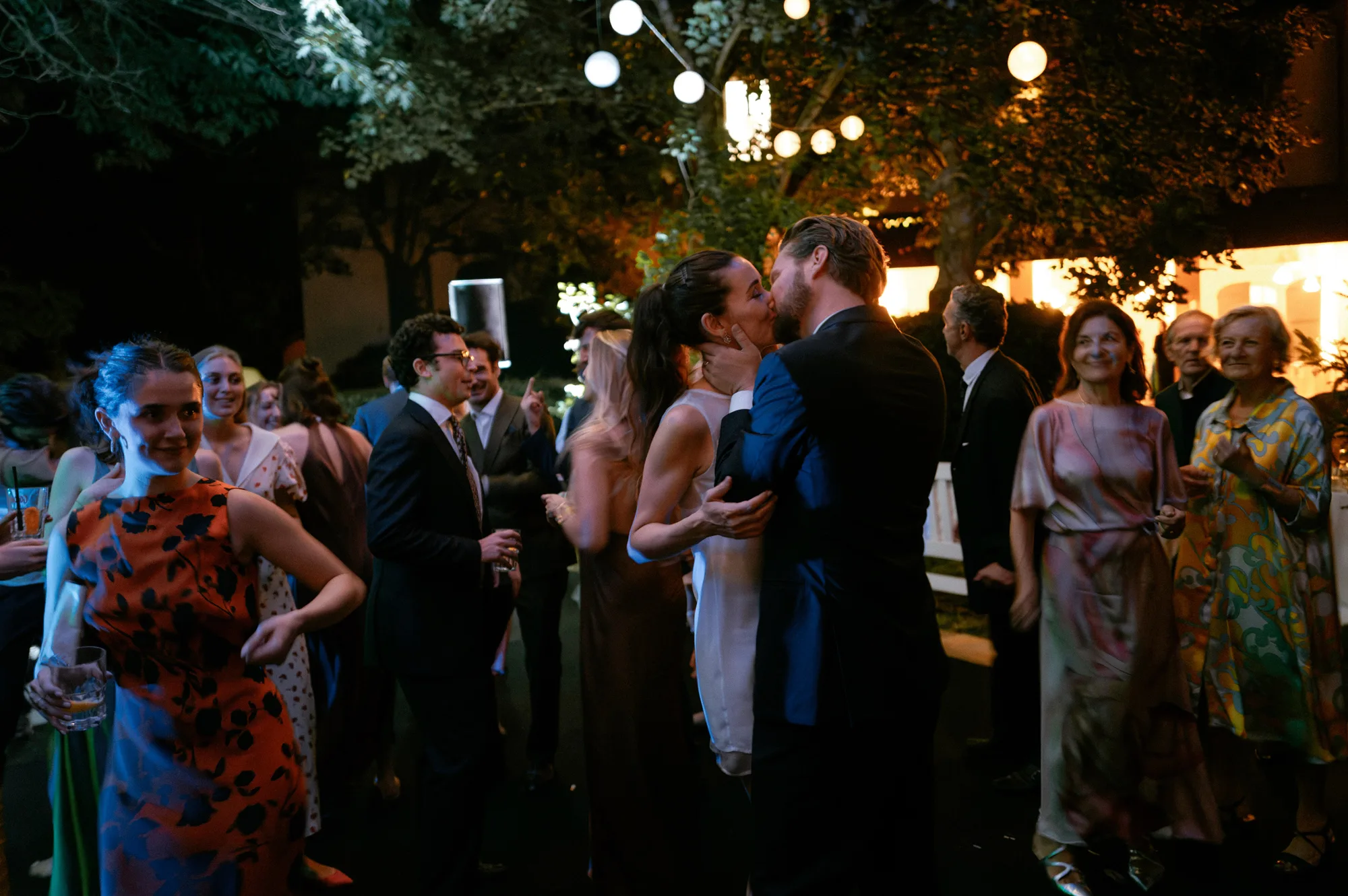 Bride in a mini dress dancing with  and kissing her groom on the evening of her private Italian villa wedding.