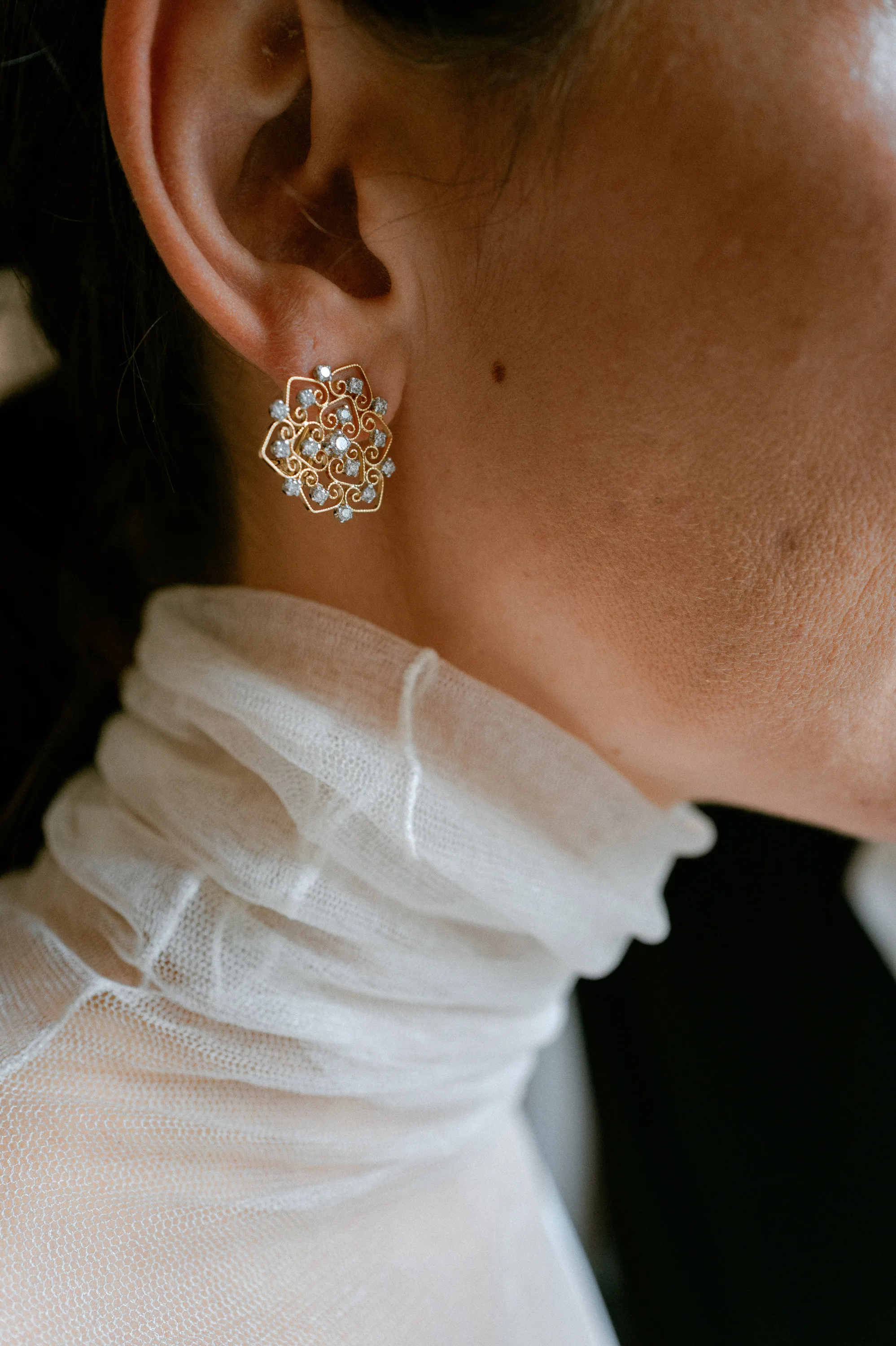 Close up shot of a bride's earrings. She wears a Cortana dress with tulle polo neck detail.