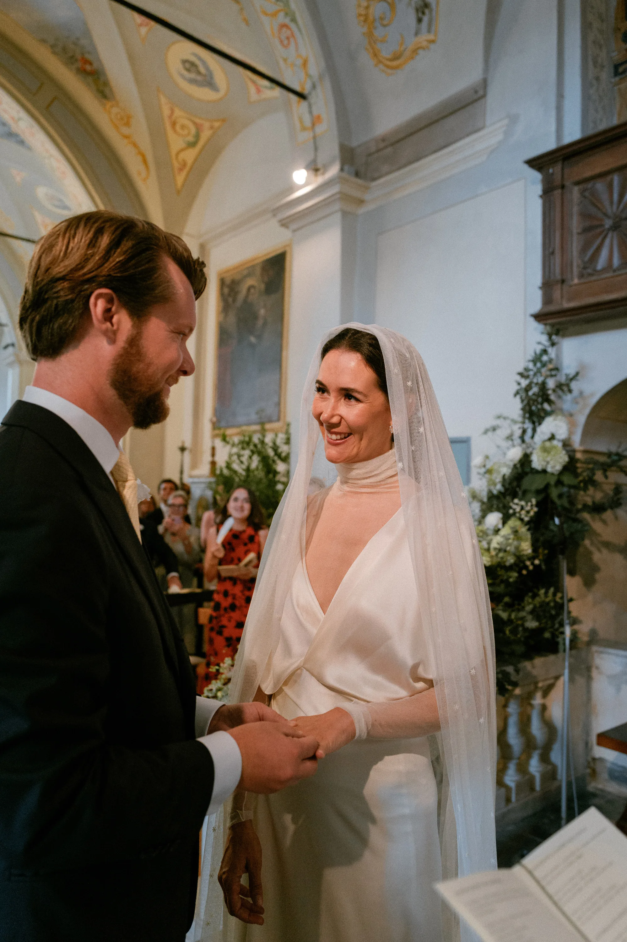 Bride and groom smiling at one another during their wedding ceremony at The Santuario della Madonna del Lago in Italy.