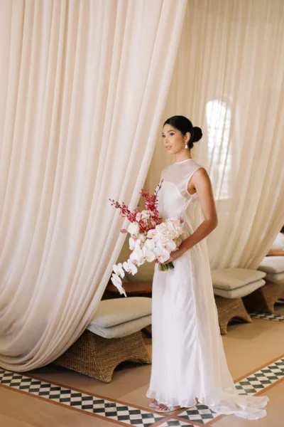 Bride in white holding a bouquet beside flowing curtains at Al Maha Resort, a Dubai destination wedding