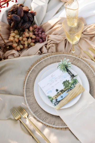 Desert wedding place setting with gold cutlery, grapes and a menu card at Al Maha Resort, Dubai, styling by Zahra Studio Events